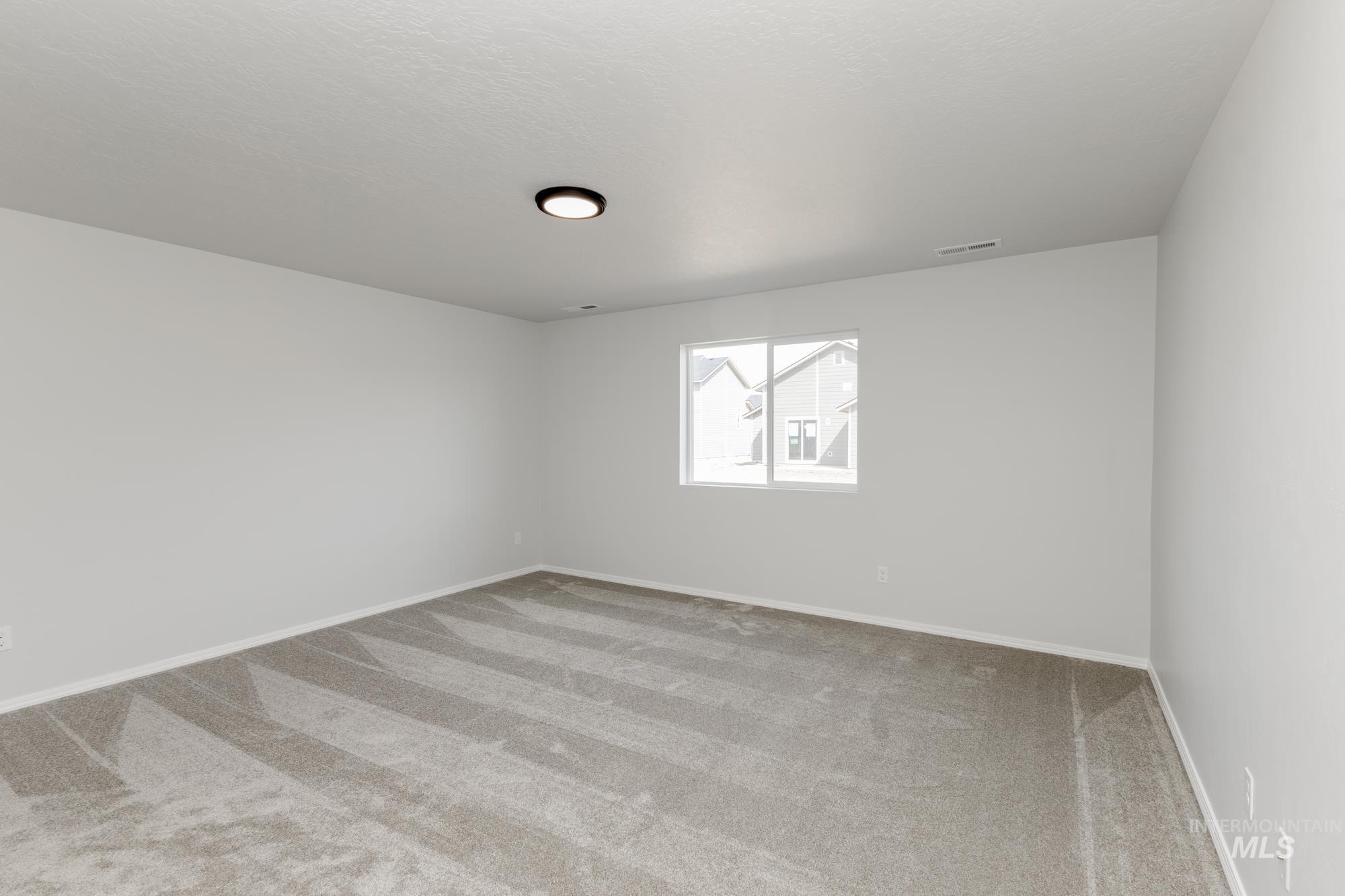 Carpeted spare room with baseboards and a textured ceiling