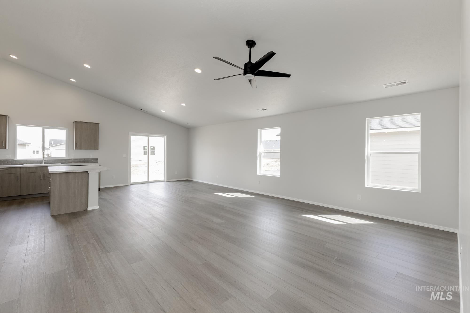 Unfurnished living room featuring dark wood finished floors, ceiling fan, high vaulted ceiling, and recessed lighting