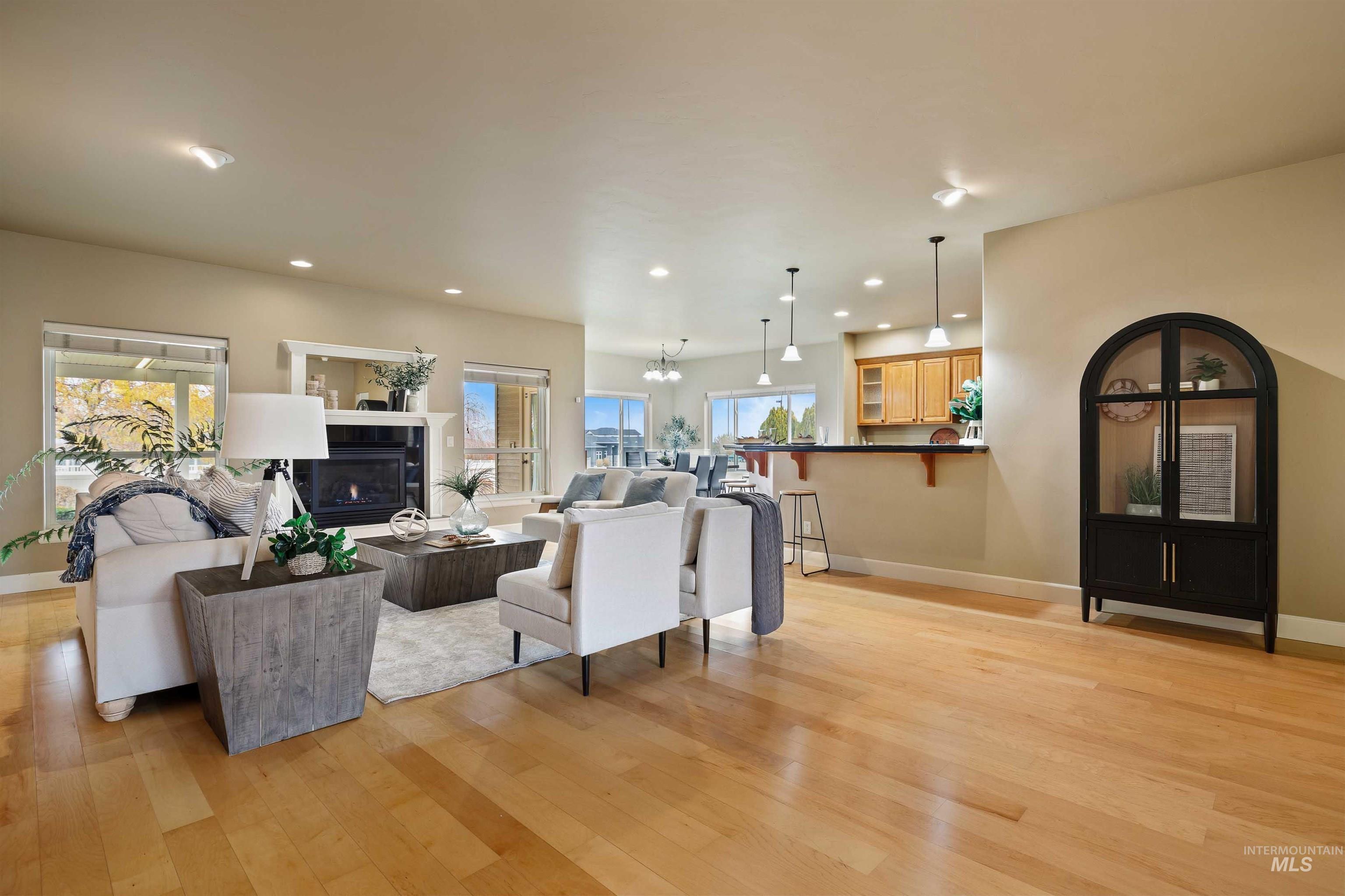 Living area featuring a tile fireplace, recessed lighting, light wood finished floors, and a chandelier