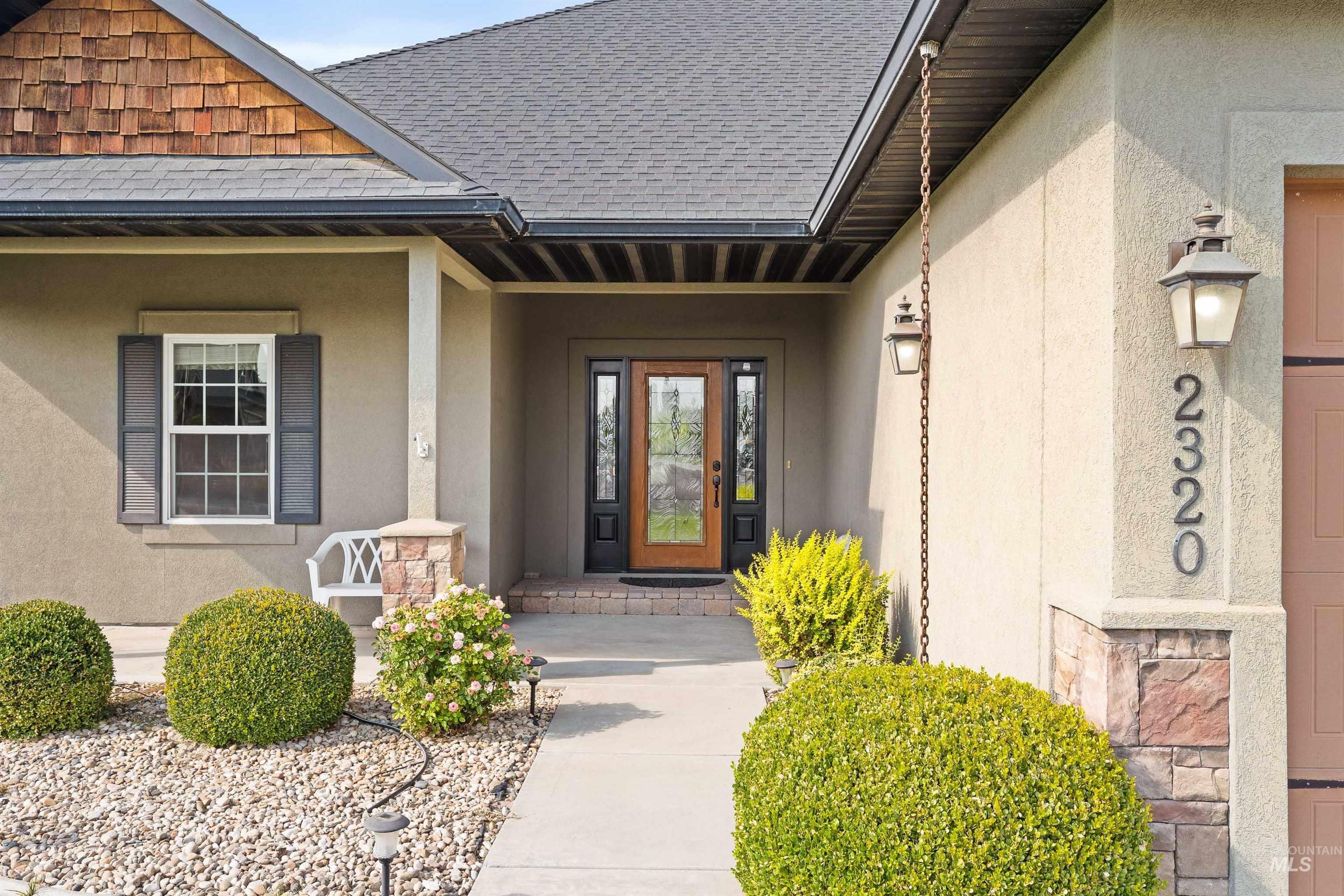 Doorway to property with stucco siding, roof with shingles, and covered porch