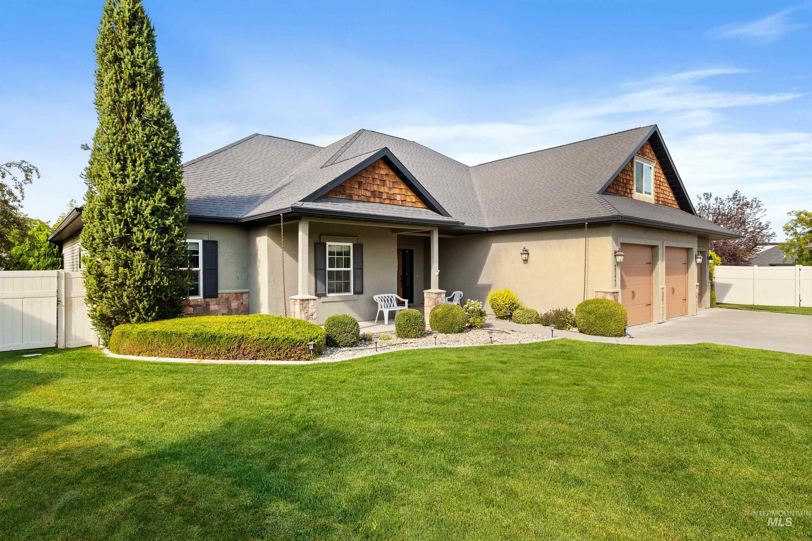 Craftsman-style house with stucco siding, covered porch, concrete driveway, and a shingled roof