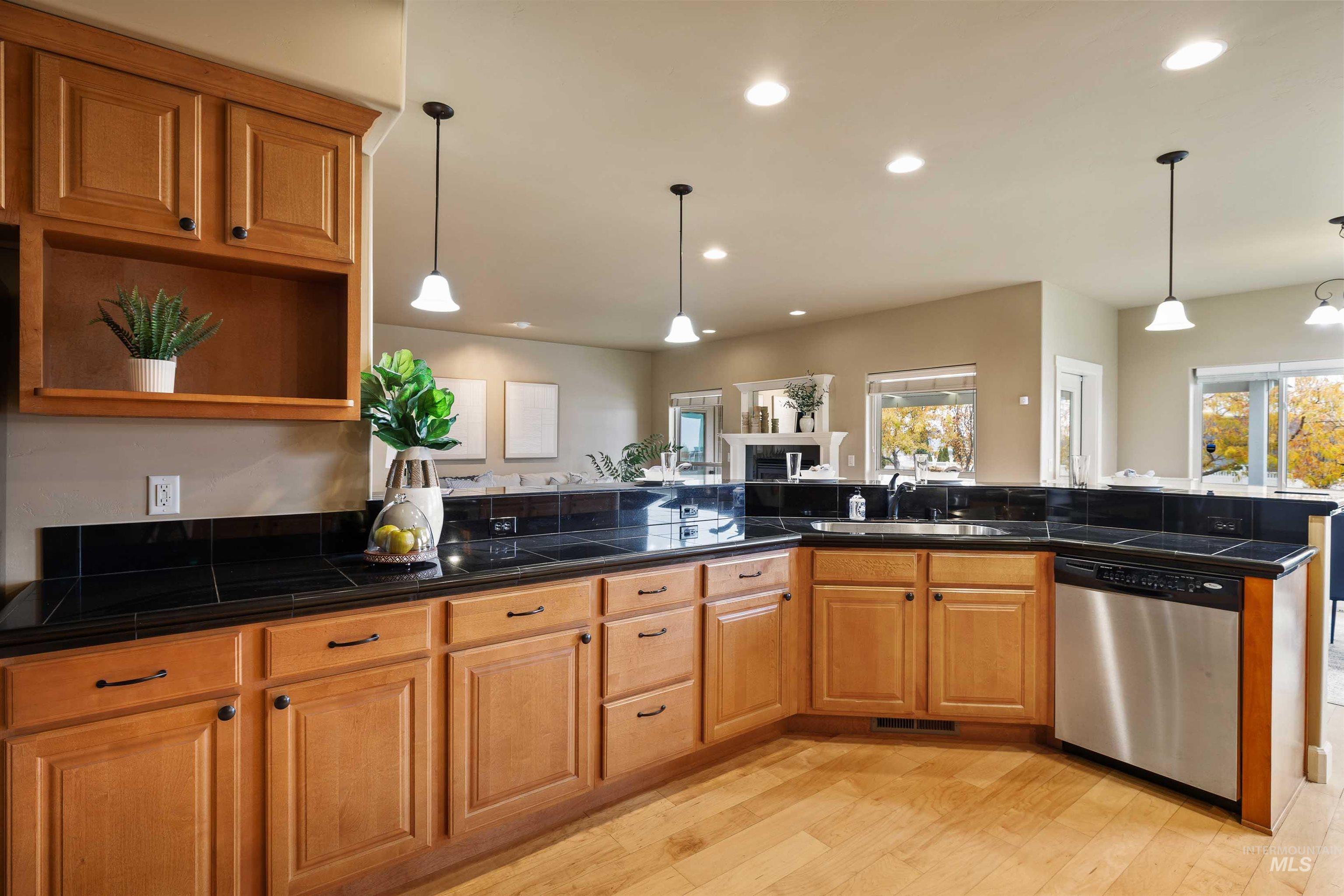 Kitchen with dishwasher, recessed lighting, light wood finished floors, brown cabinets, and pendant lighting