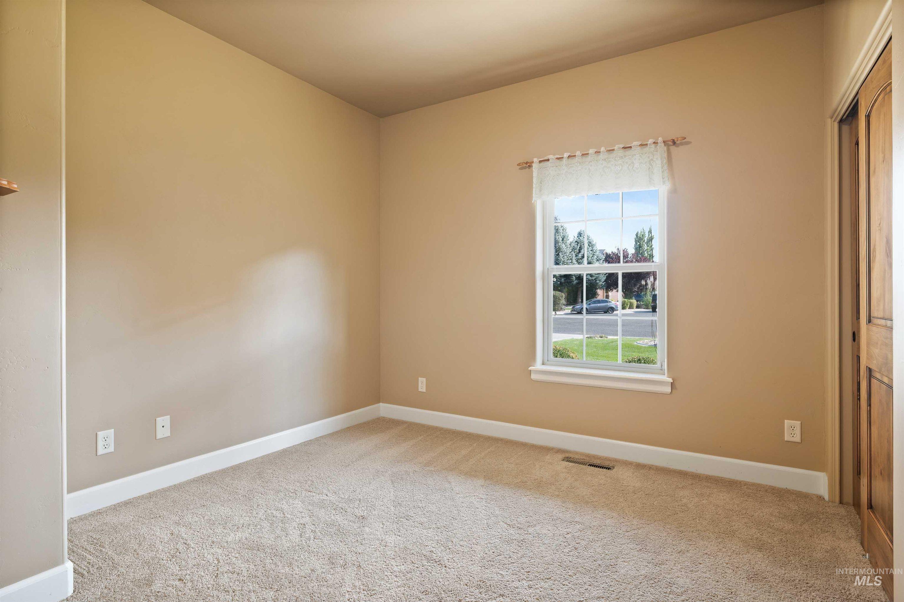 Empty room with light colored carpet and baseboards