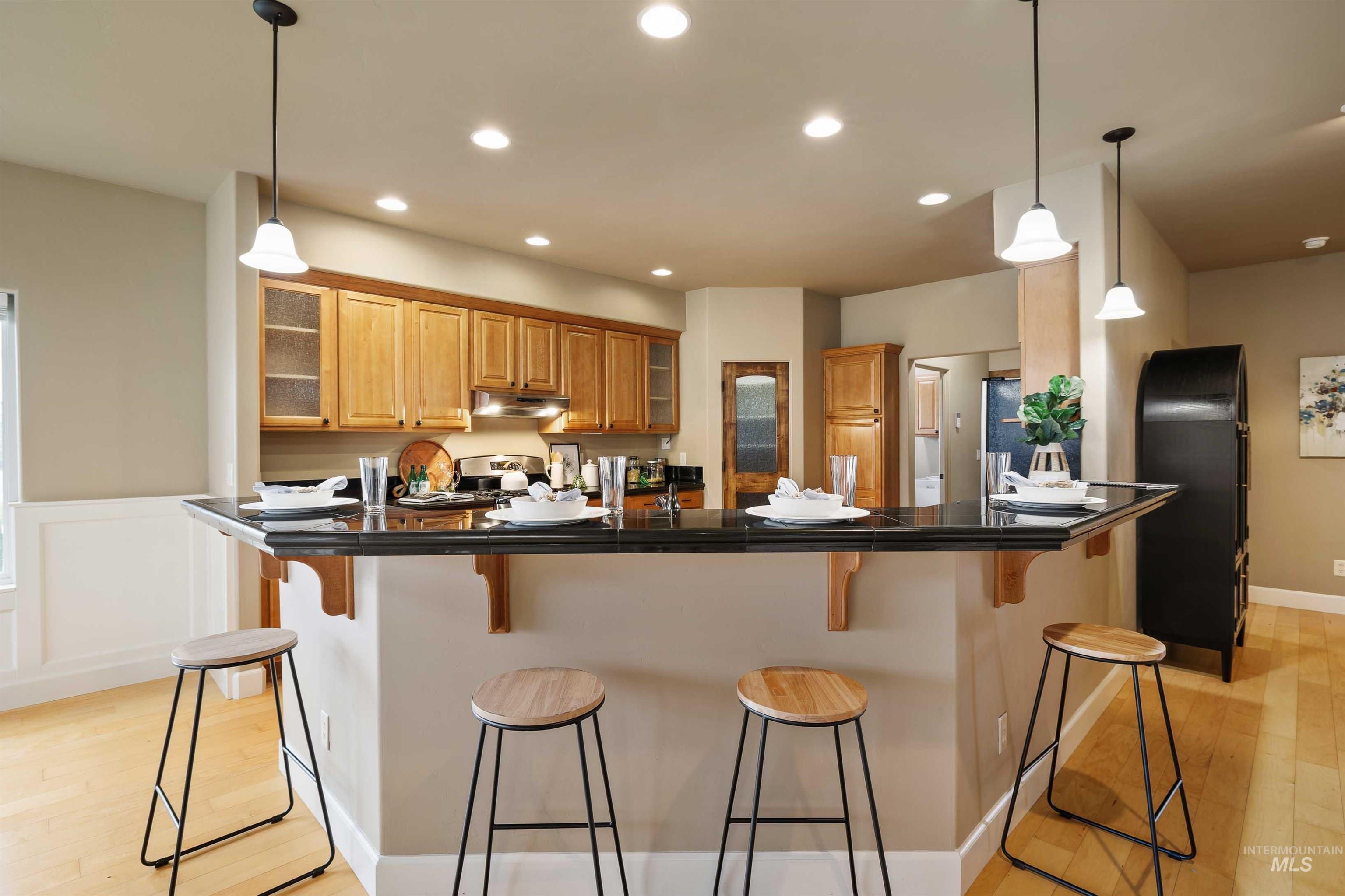 Kitchen with dark countertops, light wood finished floors, a breakfast bar area, and recessed lighting