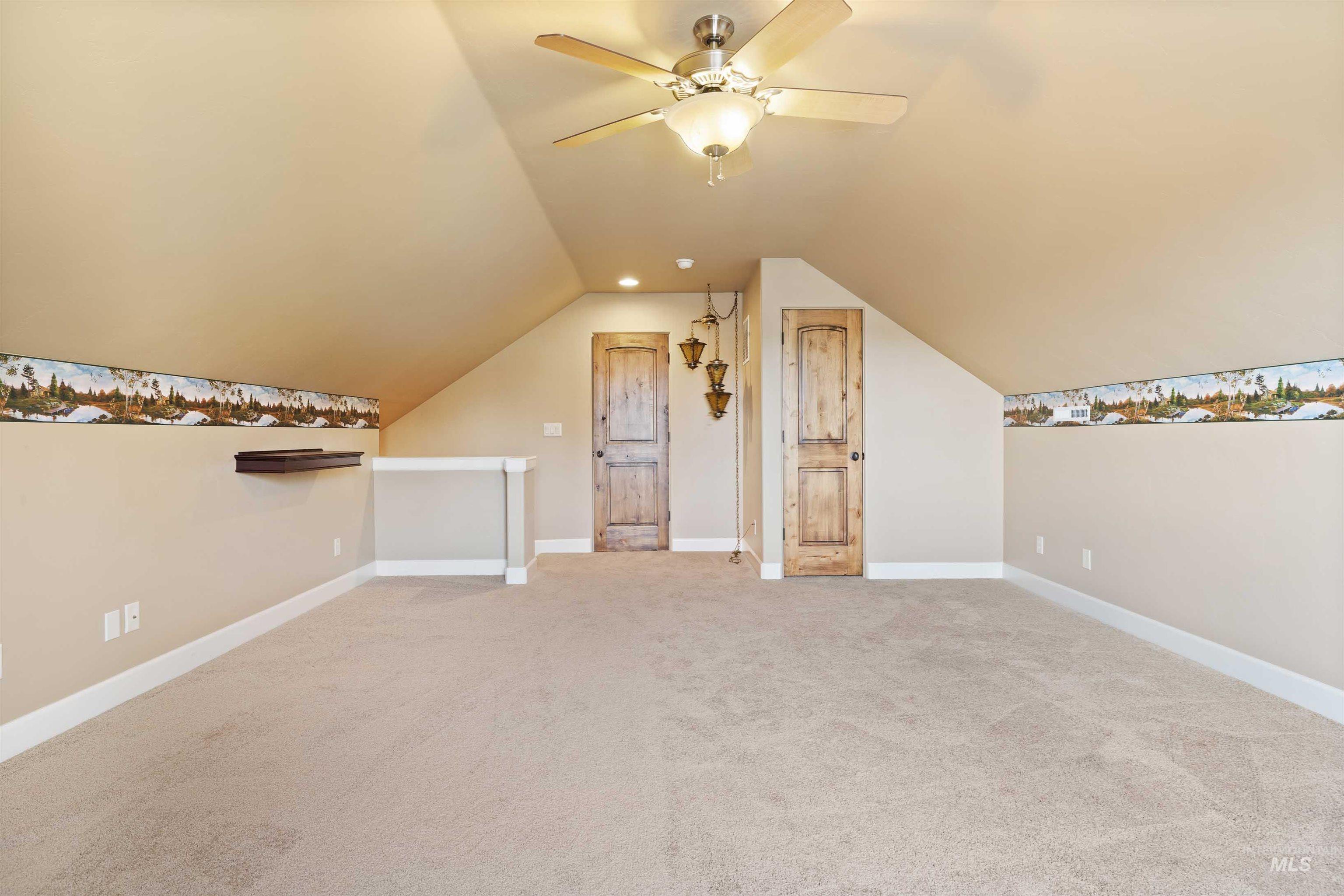 Additional living space featuring light colored carpet and vaulted ceiling