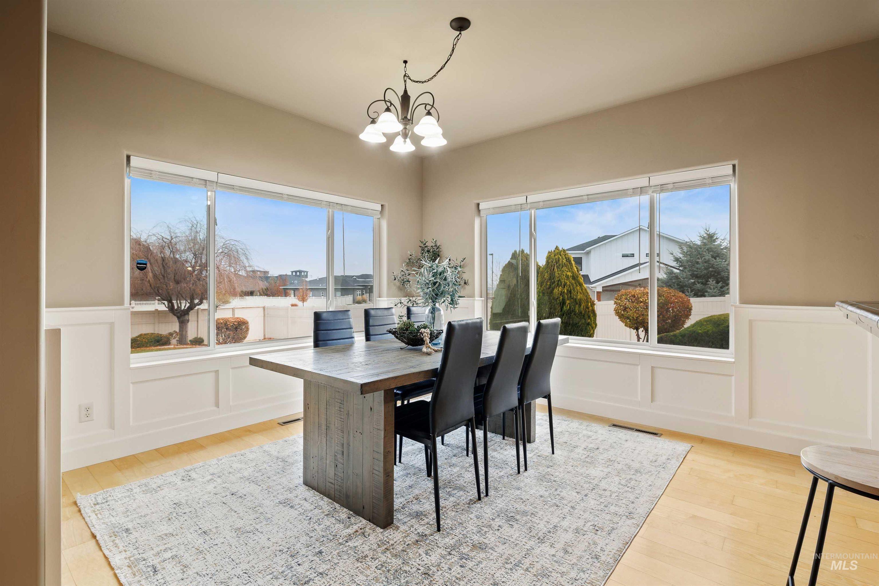 Dining space with a decorative wall, a wainscoted wall, a chandelier, and light wood-style flooring