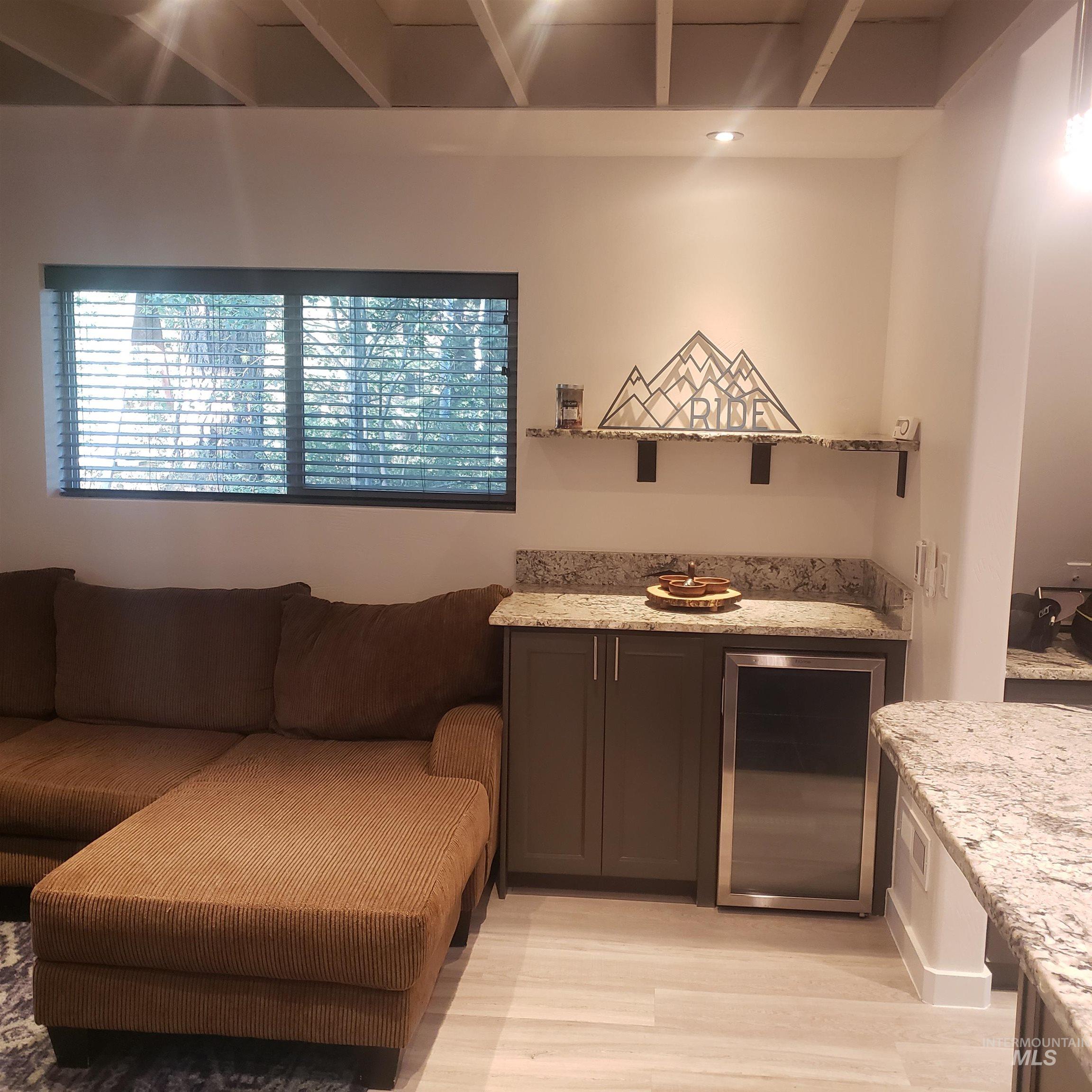 Interior space featuring light stone counters, light wood-style flooring, beverage cooler, and open floor plan