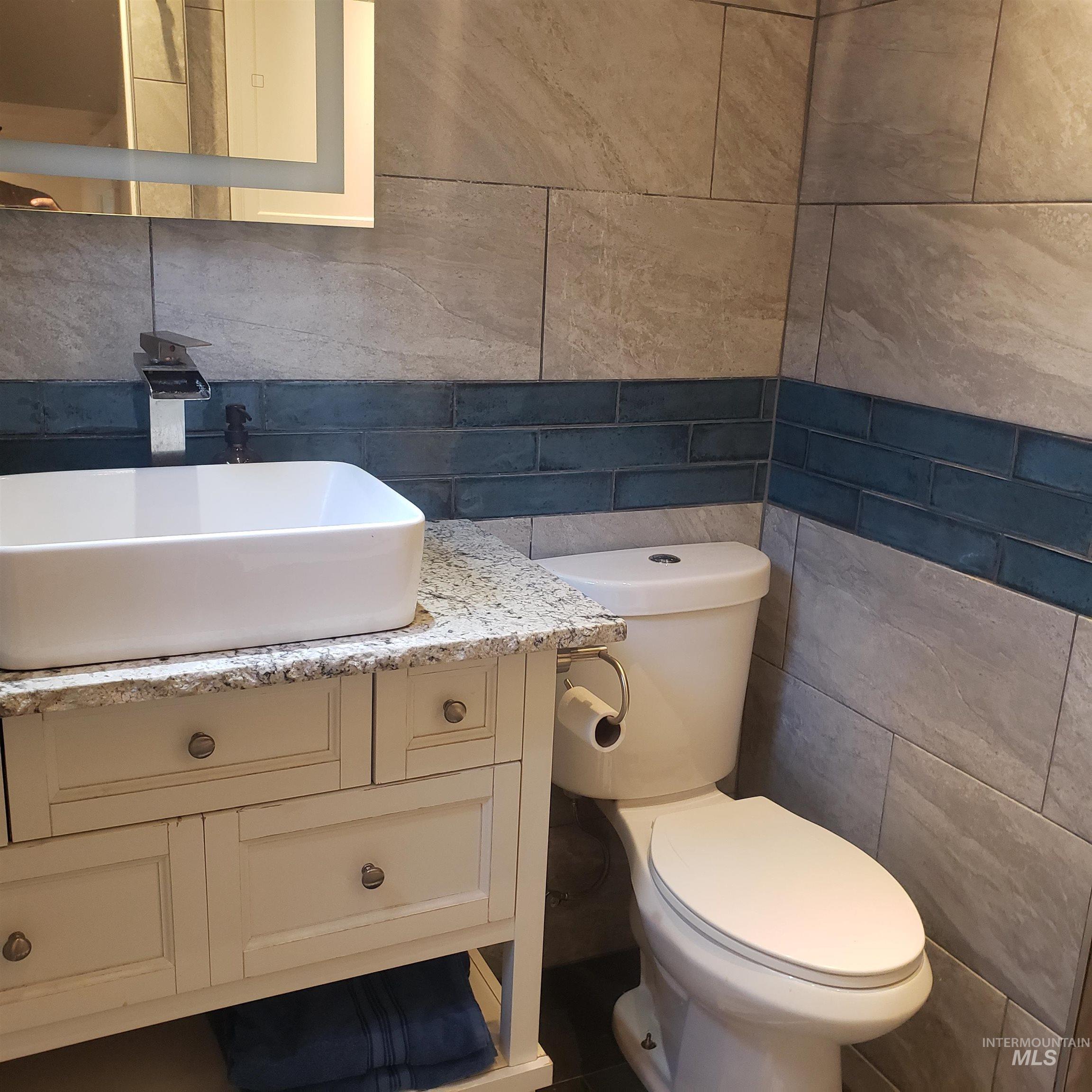 Half bathroom featuring tile walls, vanity, and tasteful backsplash