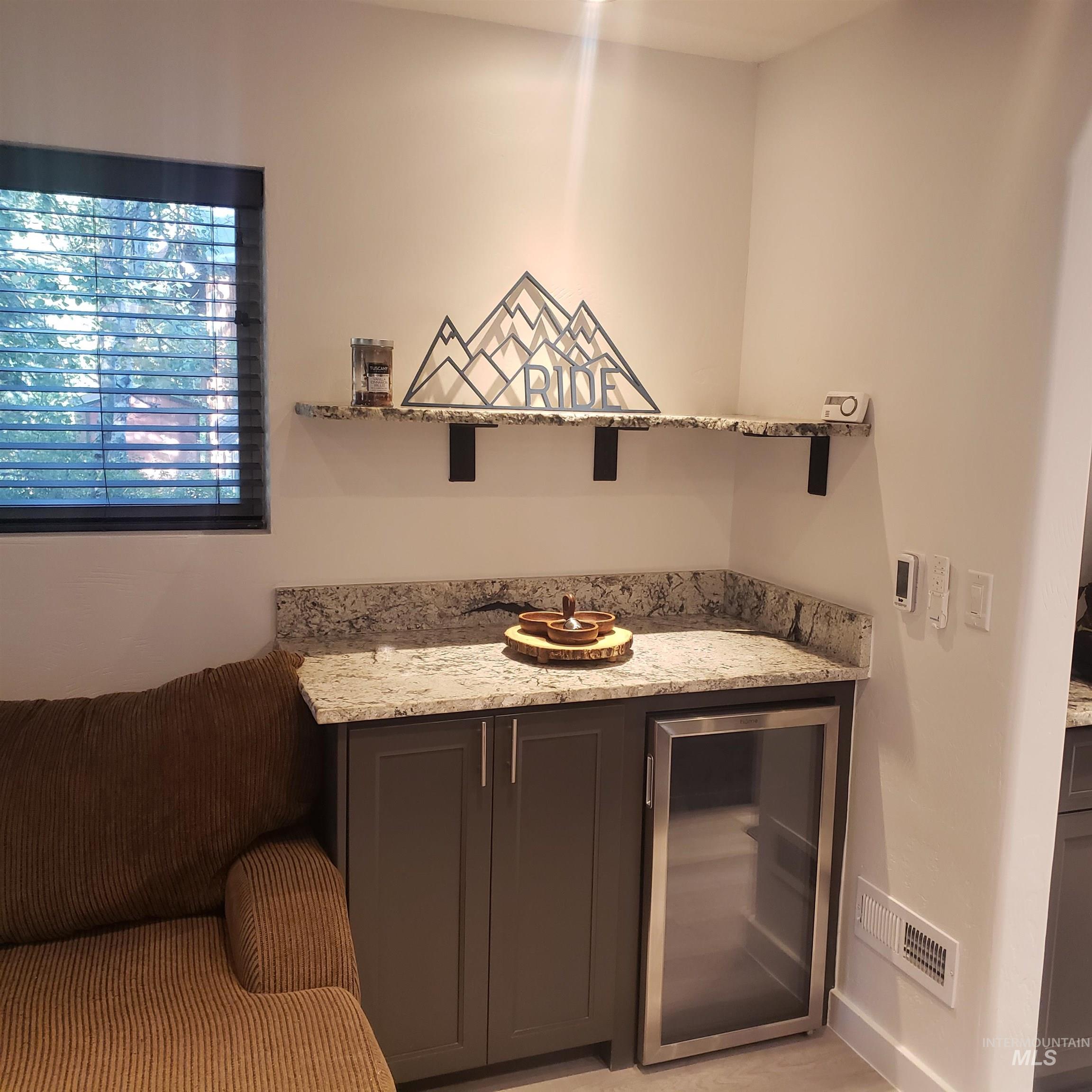 Bar area with light stone countertops and wine cooler