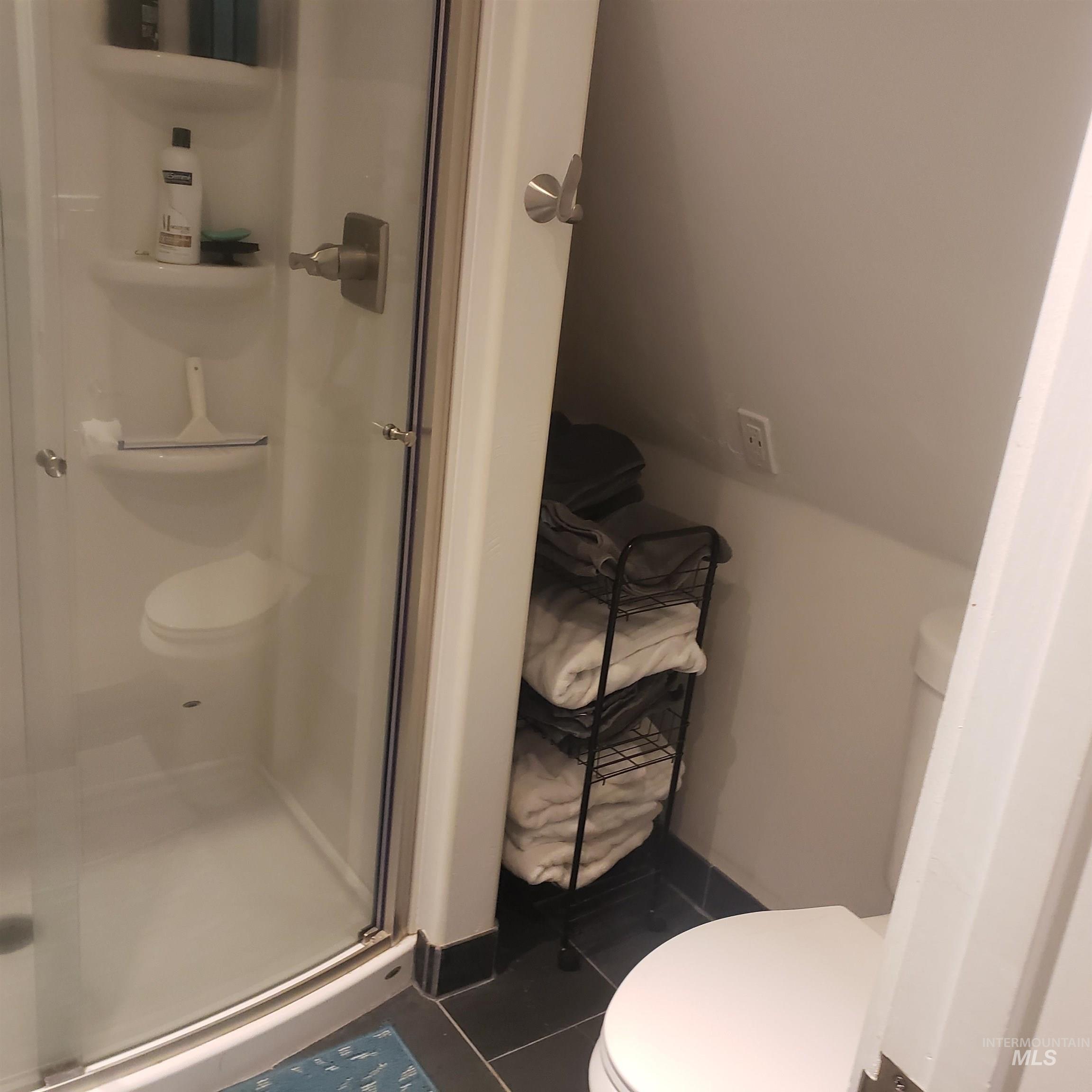 Full bath with dark tile patterned floors and a shower stall
