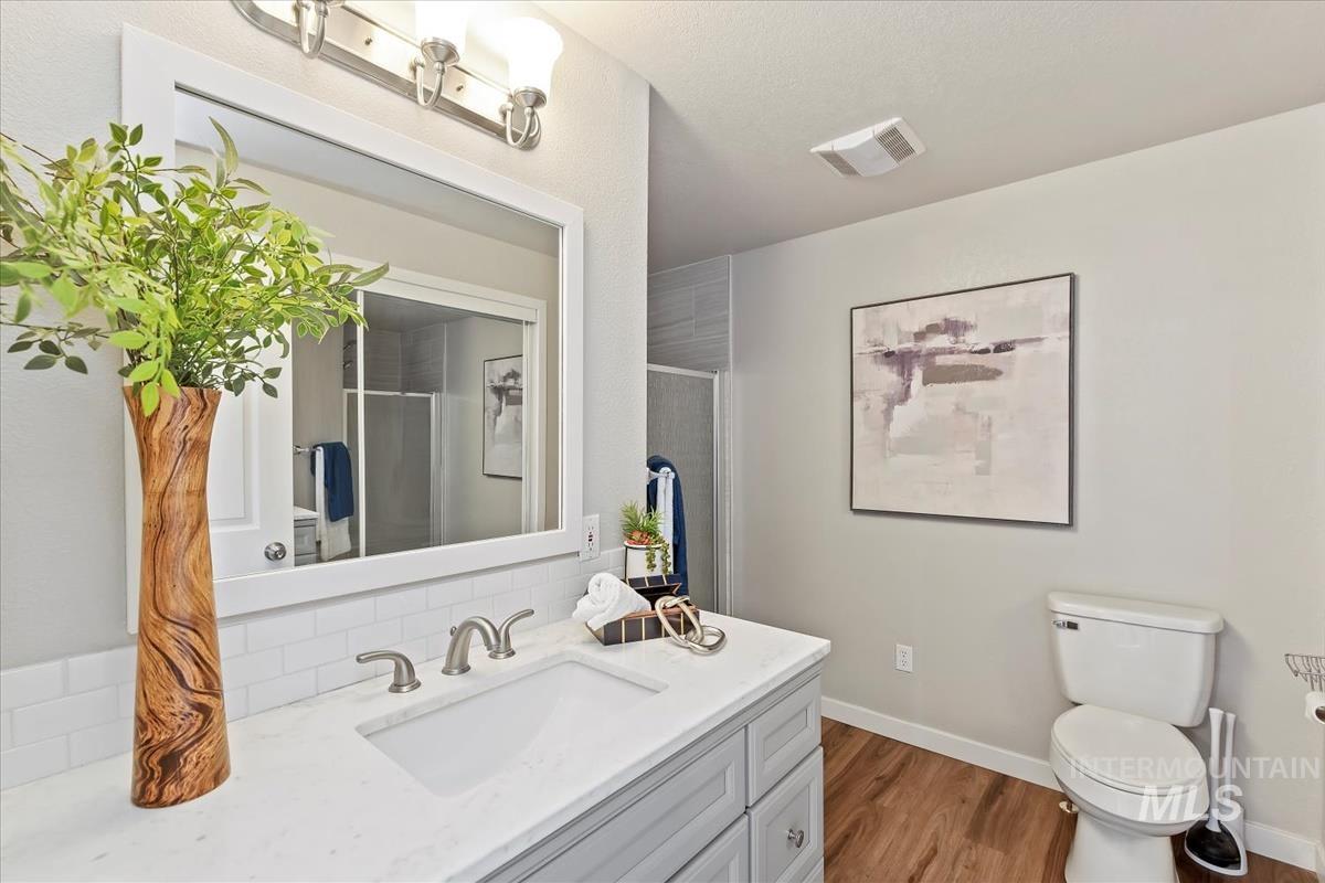 Bathroom with vanity, a shower stall, and dark wood-style flooring