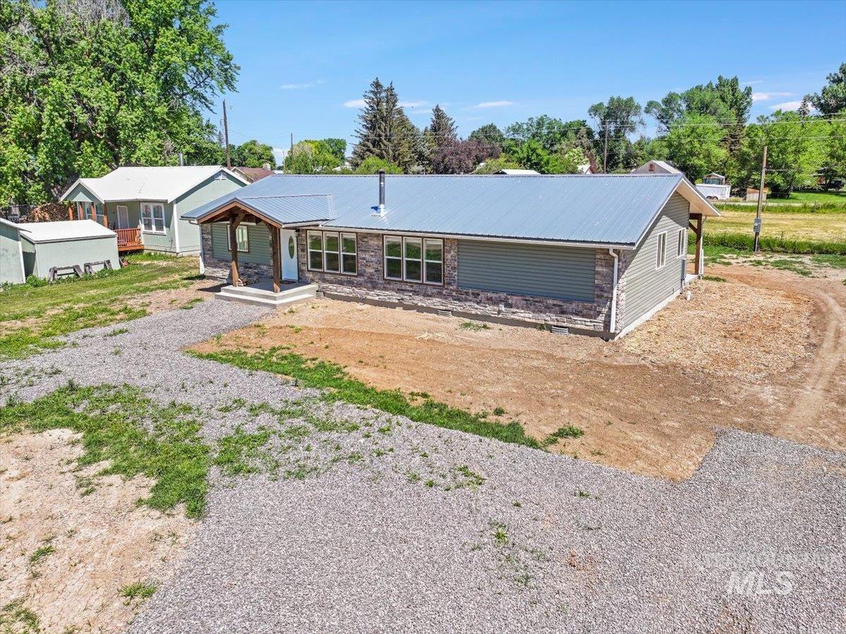 View of front of home featuring driveway, a metal roof, and covered porch