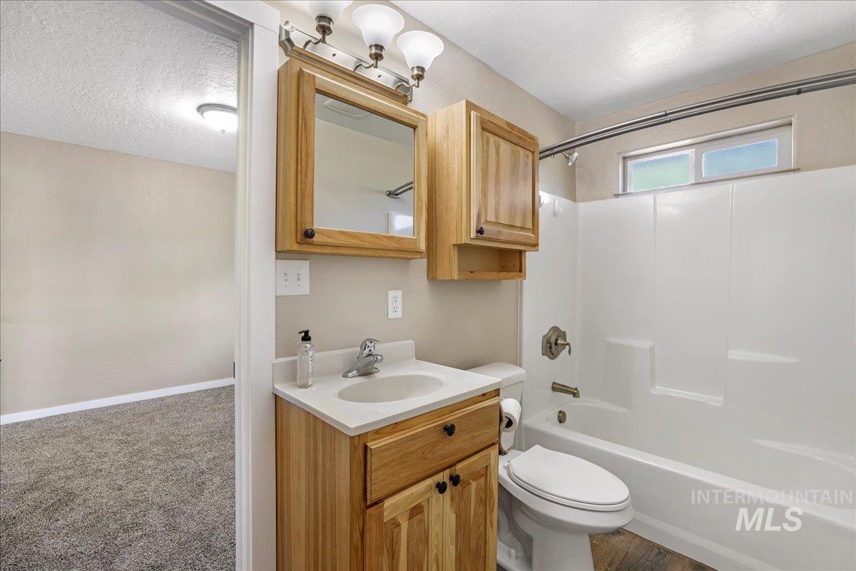 Bathroom with vanity, shower / washtub combination, and a textured ceiling