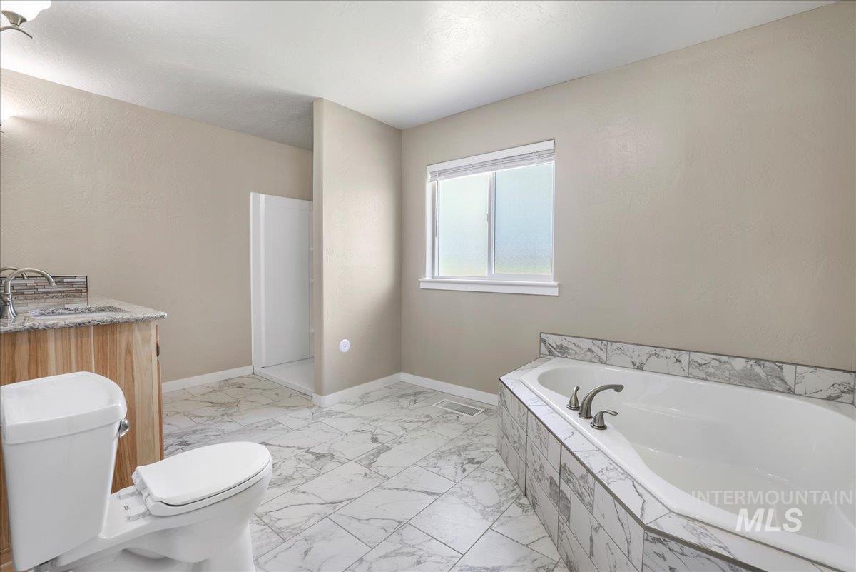 Bathroom featuring a bath and marble look tiles