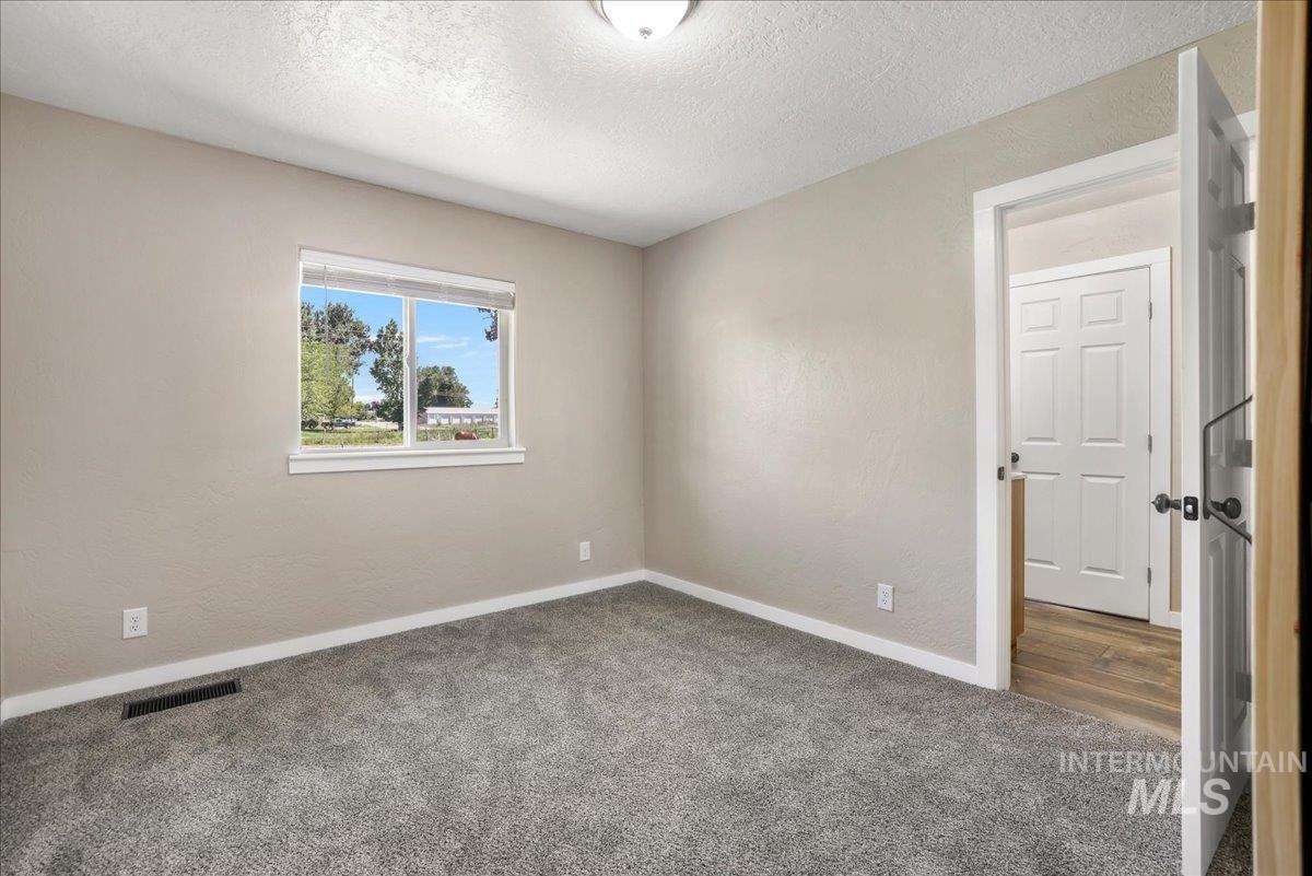 Empty room with carpet and a textured ceiling