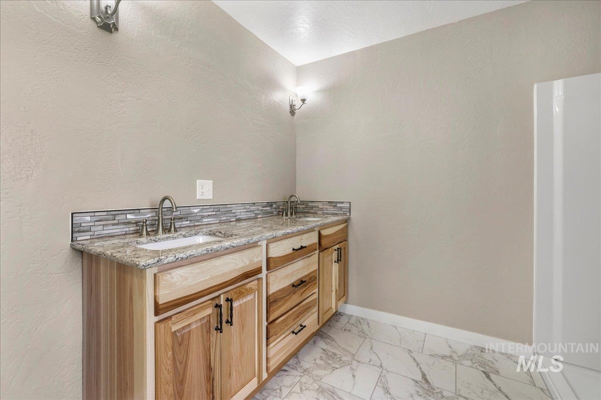 Bathroom featuring marble finish floors and double vanity