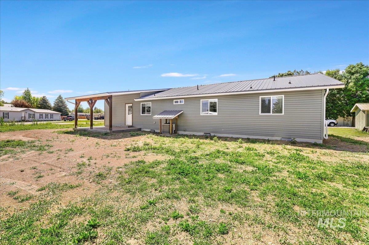 Rear view of house featuring a metal roof, a lawn, and a patio area