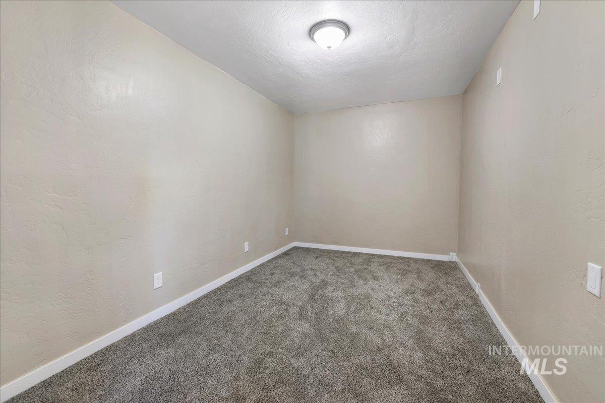 Unfurnished room with carpet flooring, a textured wall, and a textured ceiling