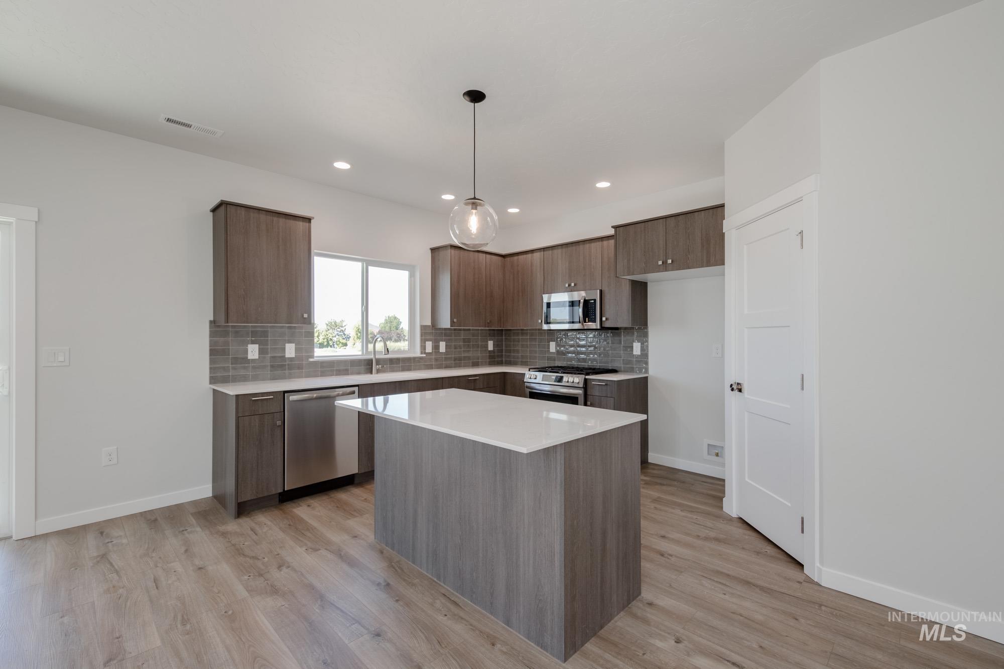 Kitchen featuring modern cabinets, tasteful backsplash, appliances with stainless steel finishes, a kitchen island, and recessed lighting