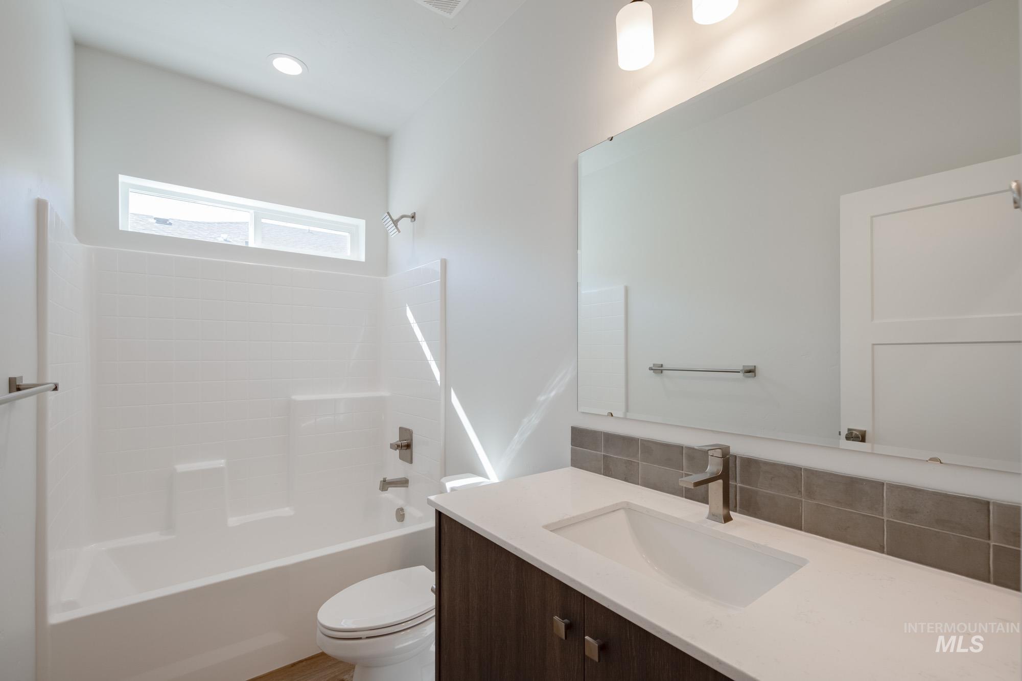 Bathroom featuring shower / tub combination, vanity, and decorative backsplash