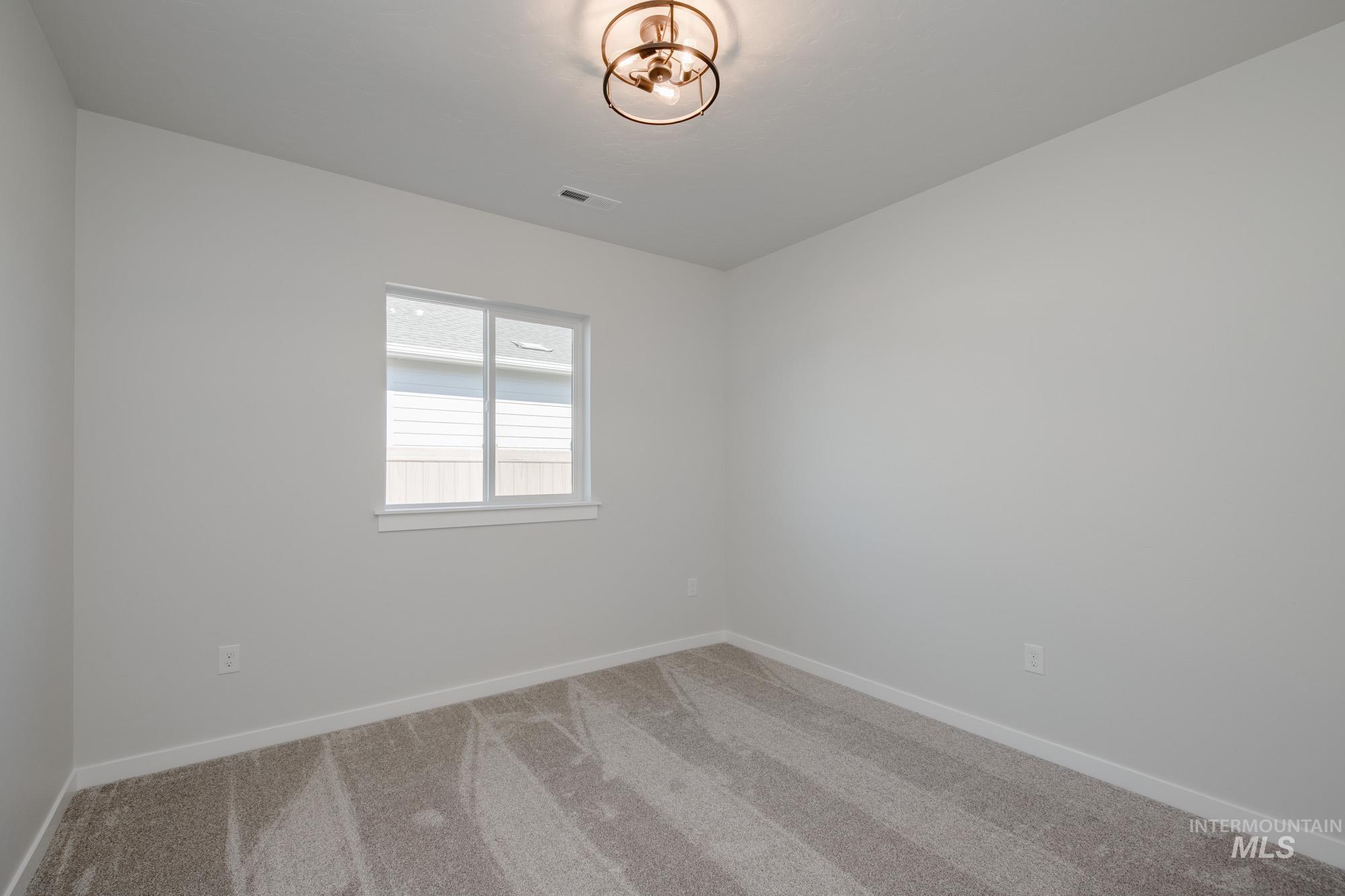 Carpeted spare room featuring baseboards