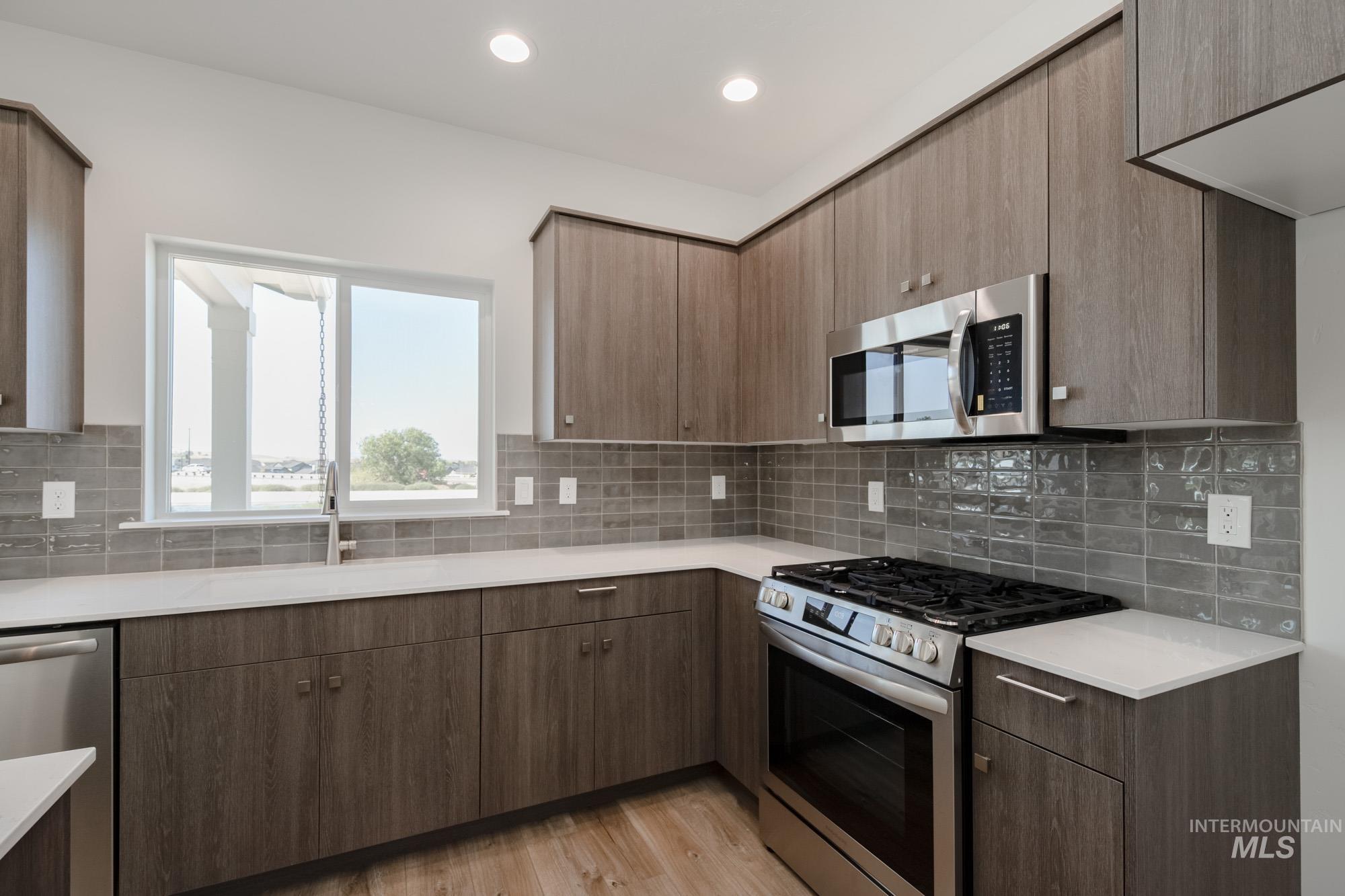Kitchen with appliances with stainless steel finishes, light wood-style floors, modern cabinets, decorative backsplash, and recessed lighting