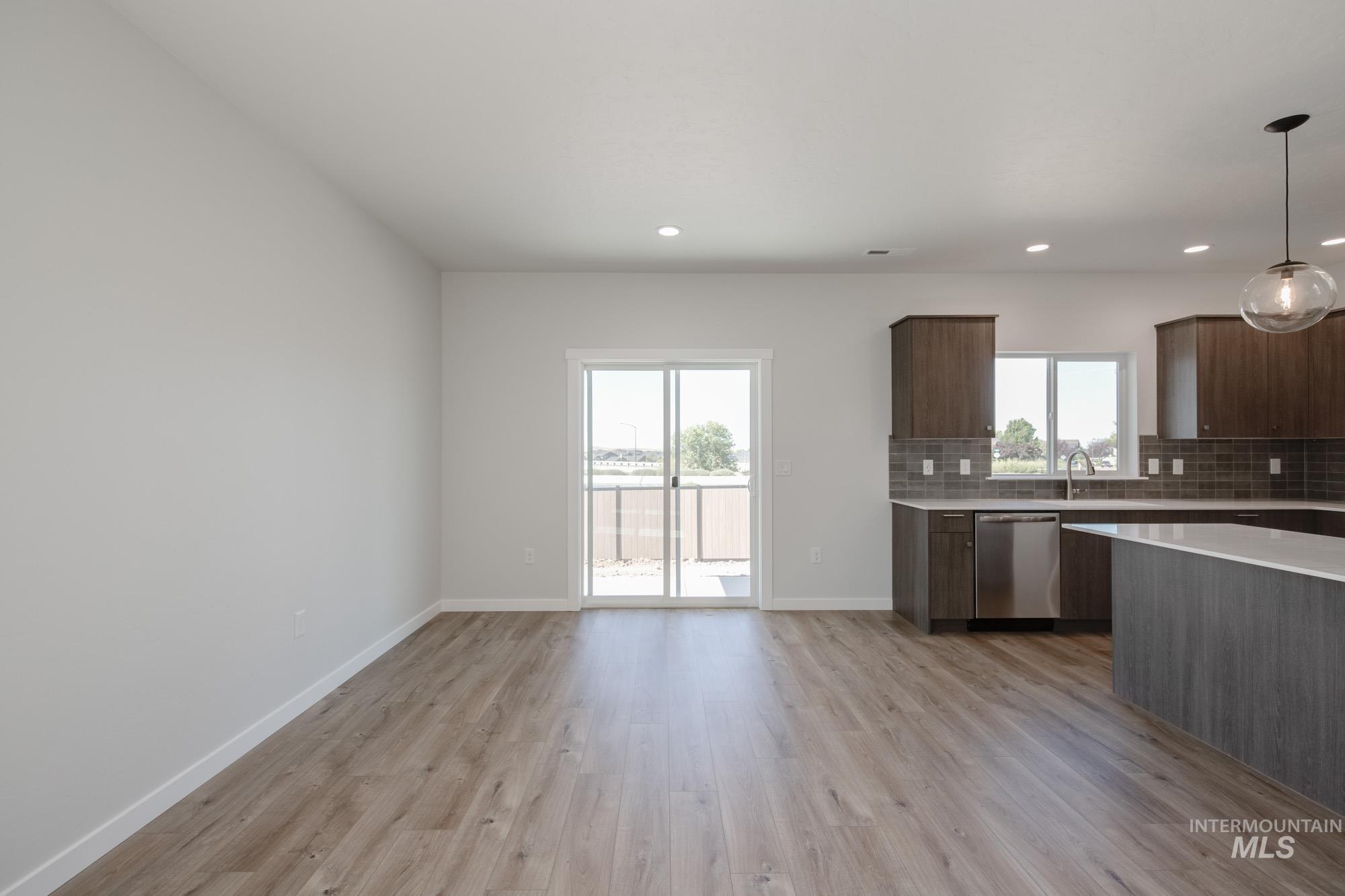 Kitchen featuring decorative backsplash, pendant lighting, dark brown cabinets, light wood-type flooring, and dishwasher