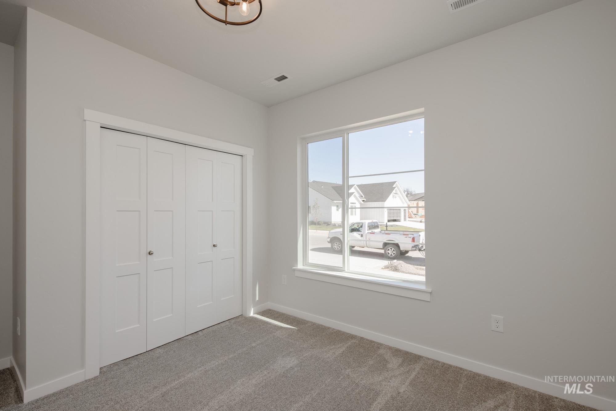Unfurnished bedroom with carpet, a closet, and a residential view