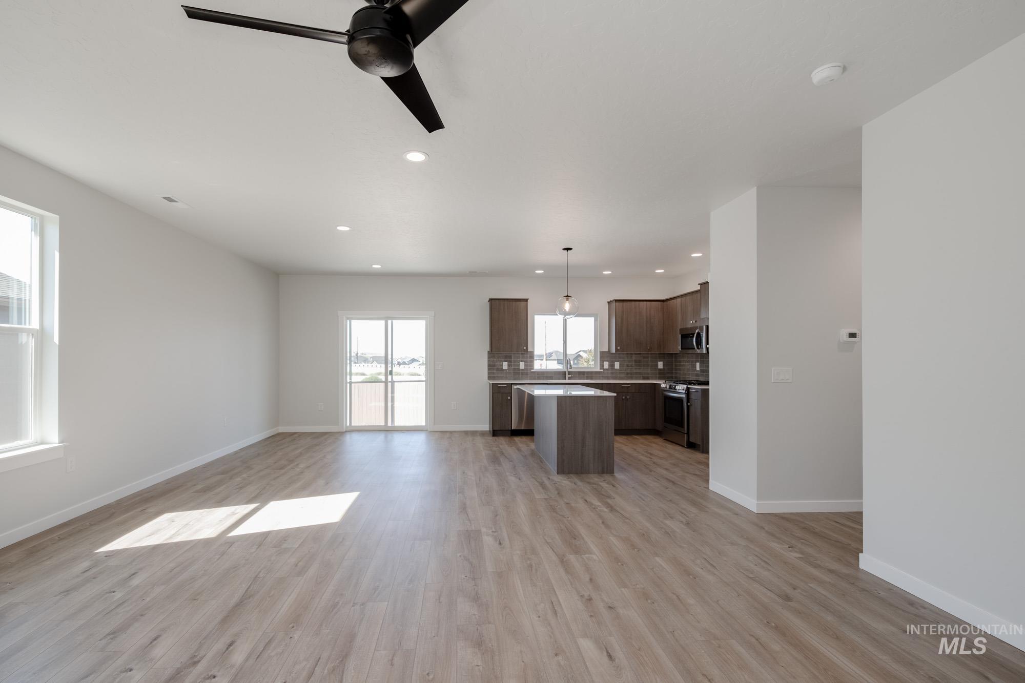 Unfurnished living room featuring a ceiling fan, light wood finished floors, and recessed lighting