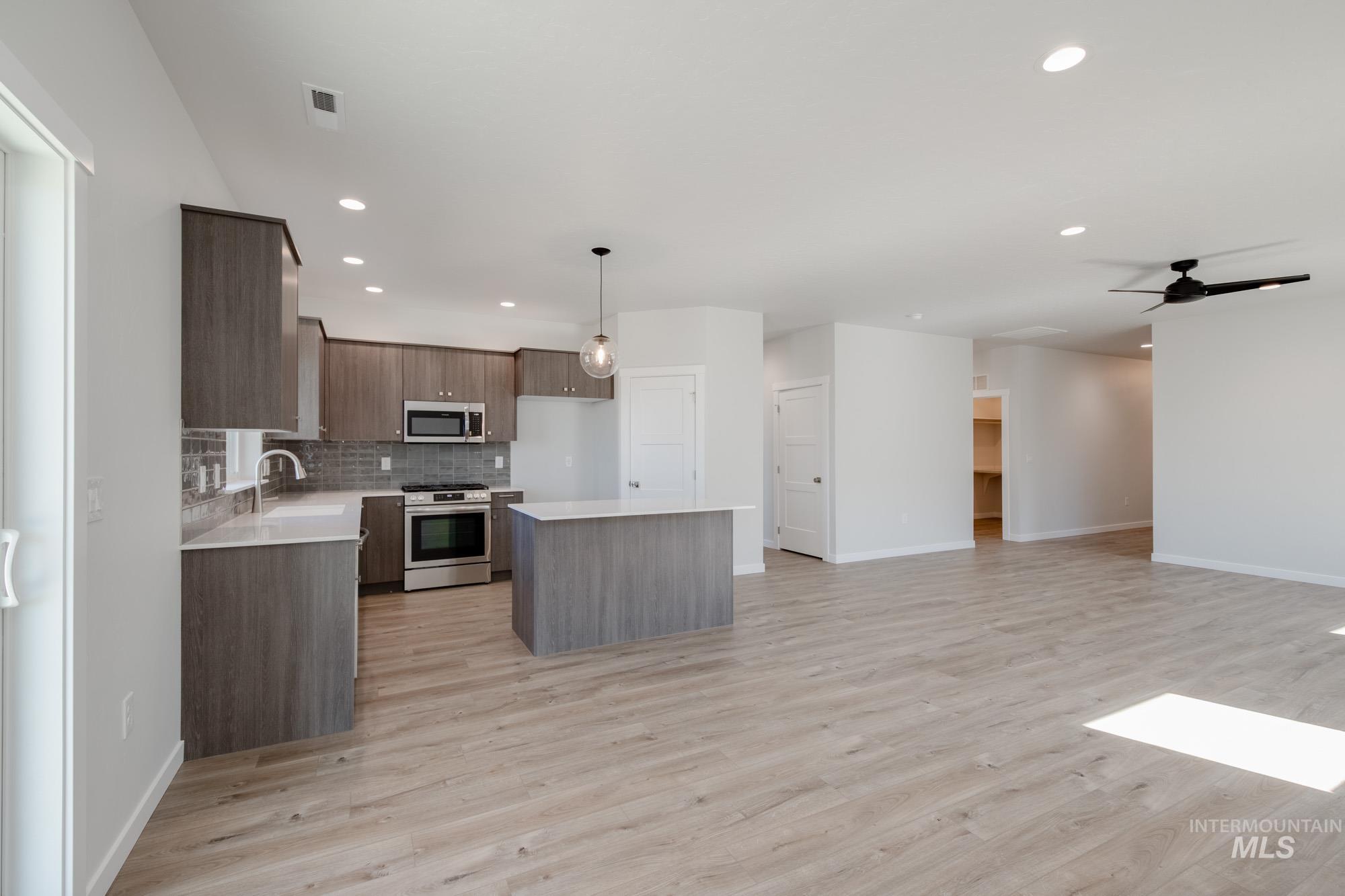 Kitchen with a center island, hanging light fixtures, backsplash, modern cabinets, and stainless steel appliances