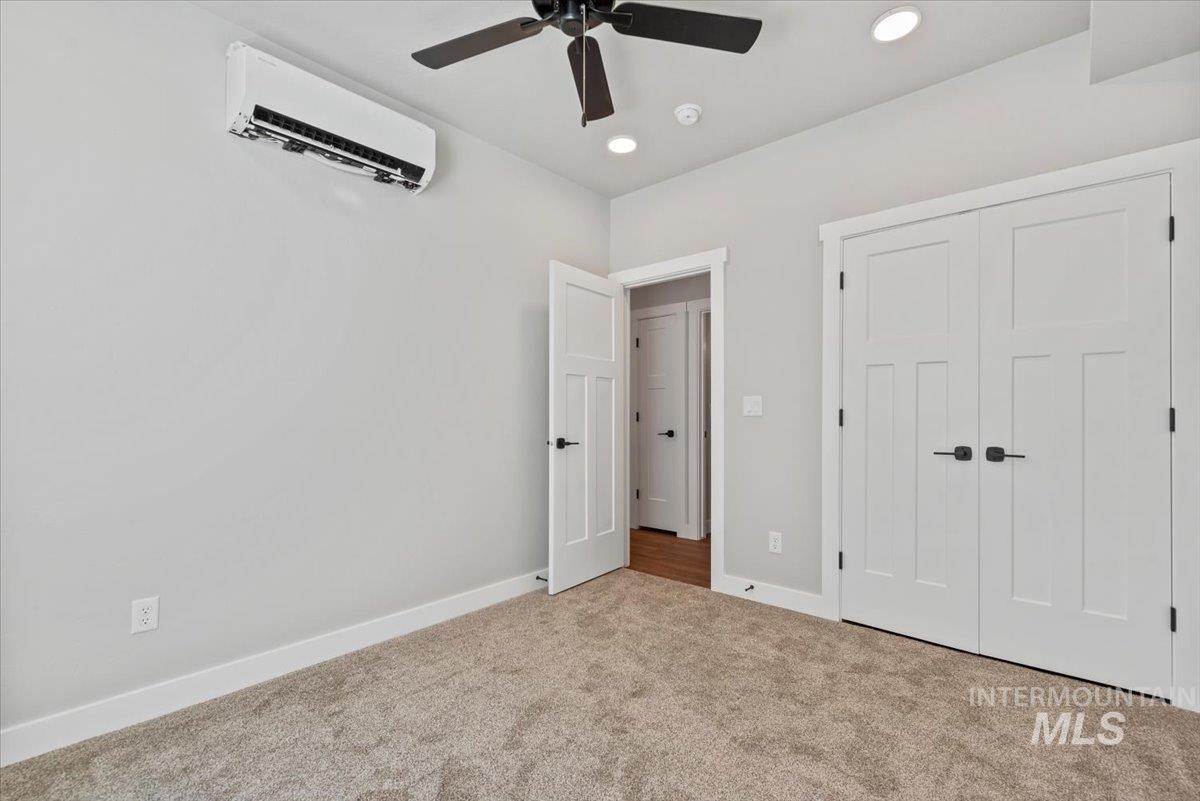 ADU bedroom featuring a wall mounted AC, carpet floors, ceiling fan, recessed lighting, and a closet