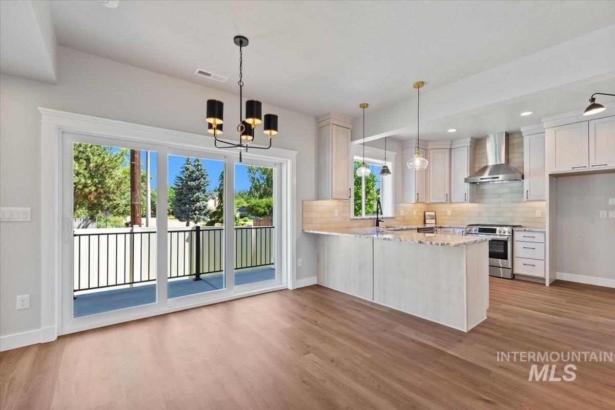 Kitchen with wall chimney exhaust hood, stainless steel range oven, decorative backsplash, light wood-style floors, and recessed lighting