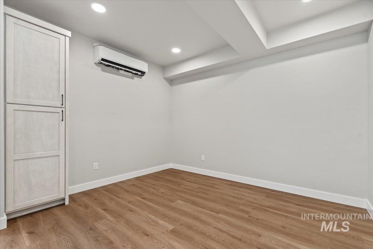 Finished below grade area featuring a wall mounted AC, wood finished floors, and recessed lighting