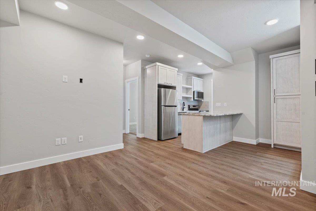 Kitchen featuring appliances with stainless steel finishes, a peninsula, open shelves, recessed lighting, and light wood-style flooring