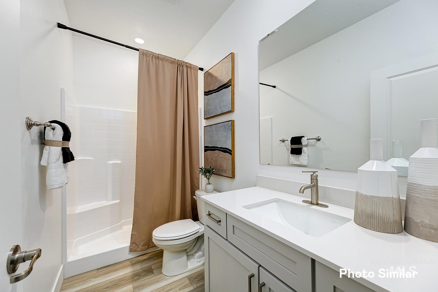 Bathroom featuring a stall shower, vanity, and light wood-style floors