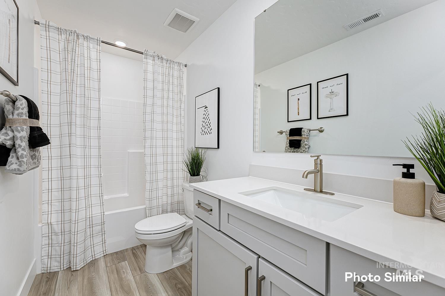 Bathroom featuring shower / bath combination with curtain, light wood-style flooring, and vanity