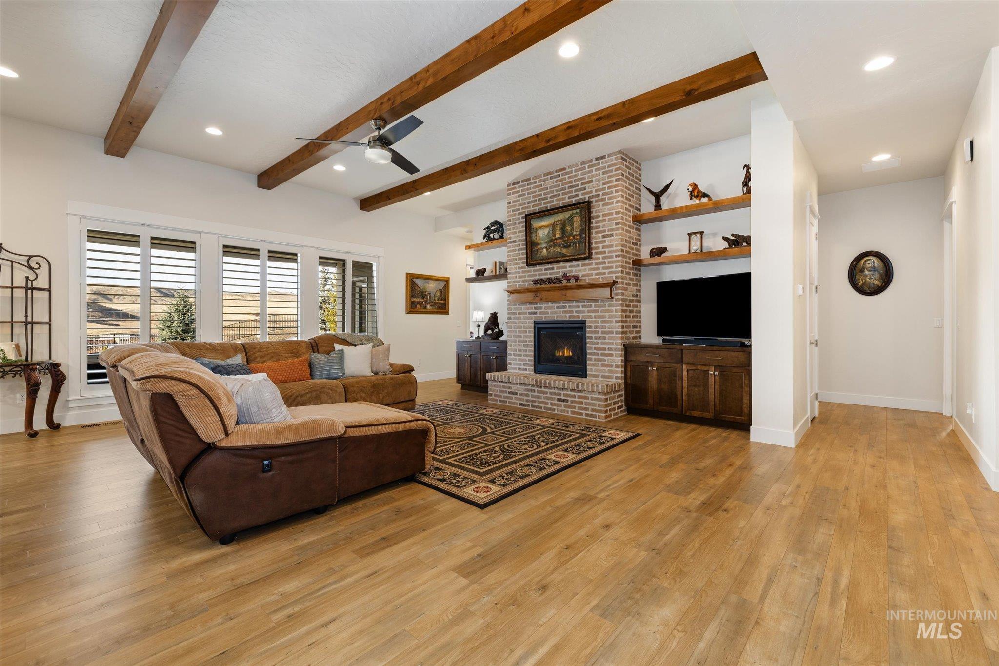 Living room with recessed lighting, a brick fireplace, light wood-style floors, a ceiling fan, and beam ceiling