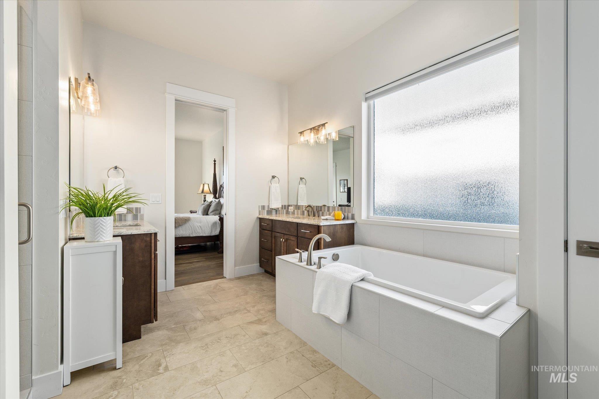 Full bathroom featuring vanity, a garden tub, and ensuite bath
