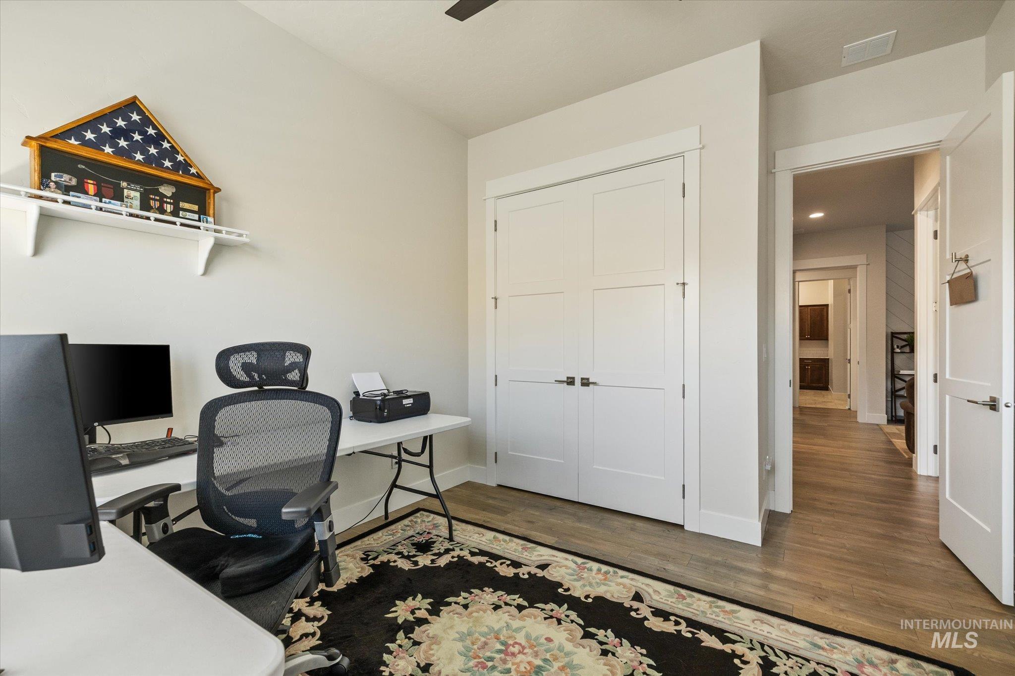 Home office featuring dark wood-style flooring and a ceiling fan