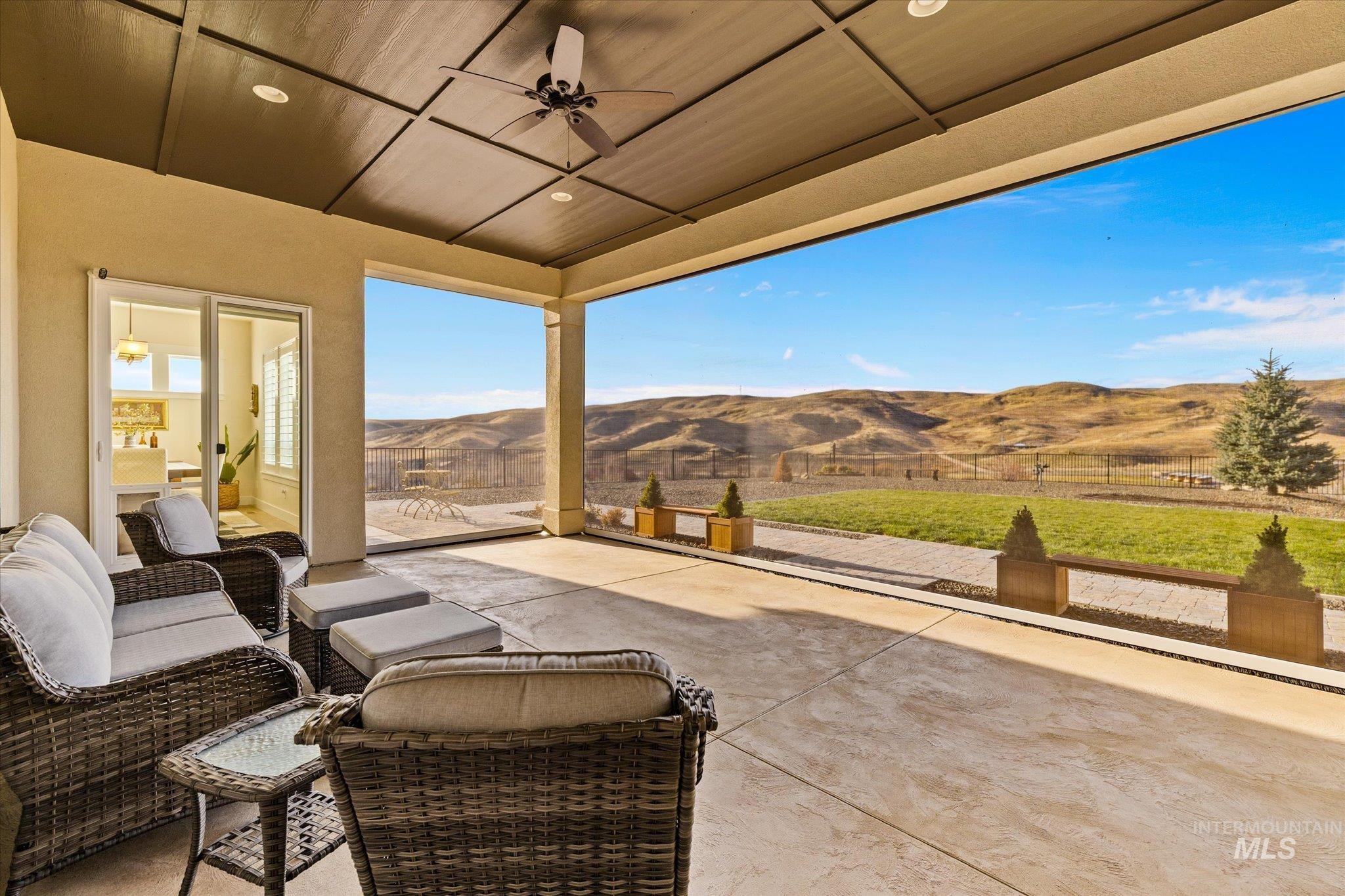Fenced backyard with a ceiling fan, a patio area, and a mountain view
