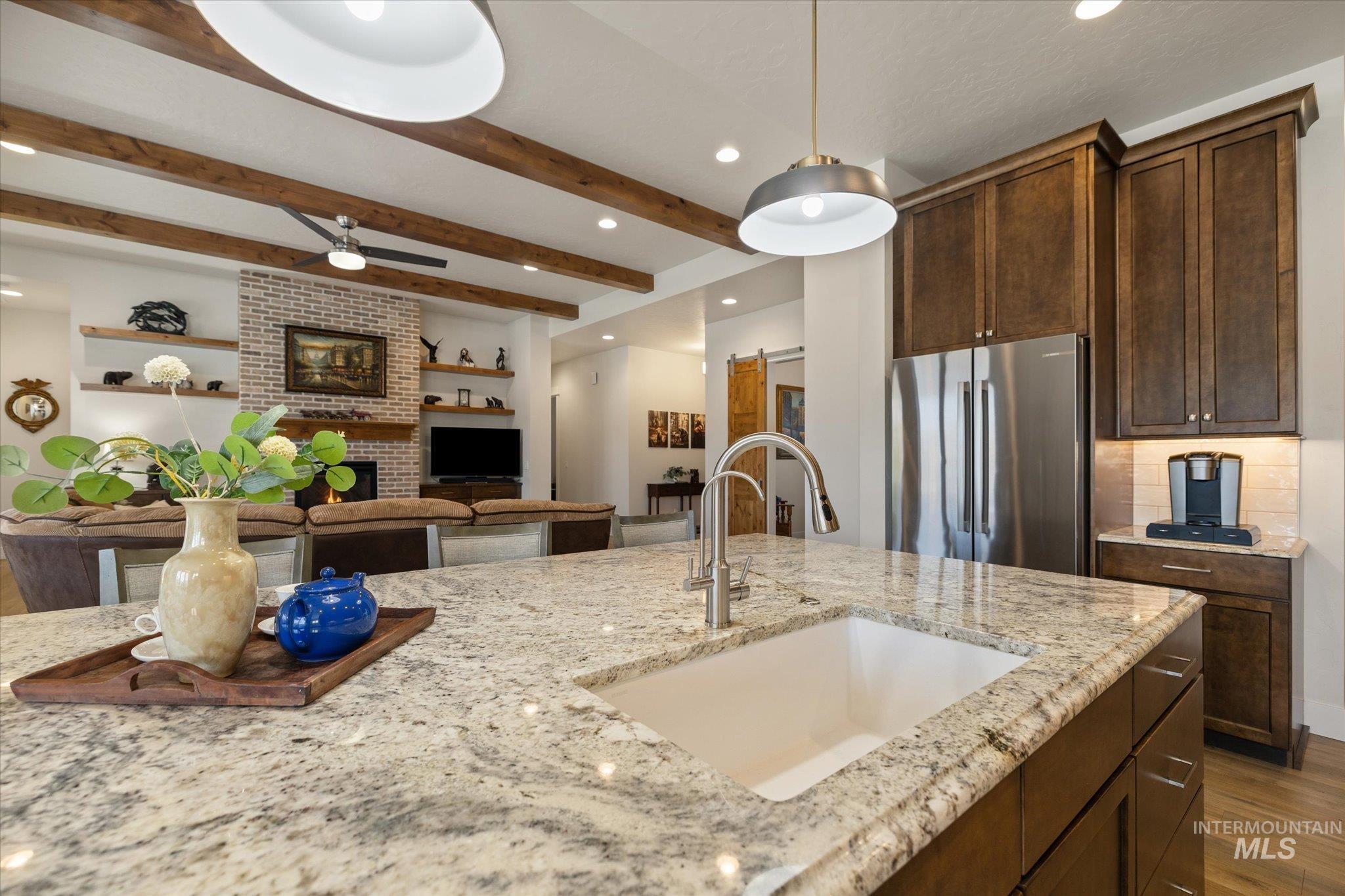 Kitchen featuring freestanding refrigerator, light stone counters, recessed lighting, open floor plan, and hanging light fixtures