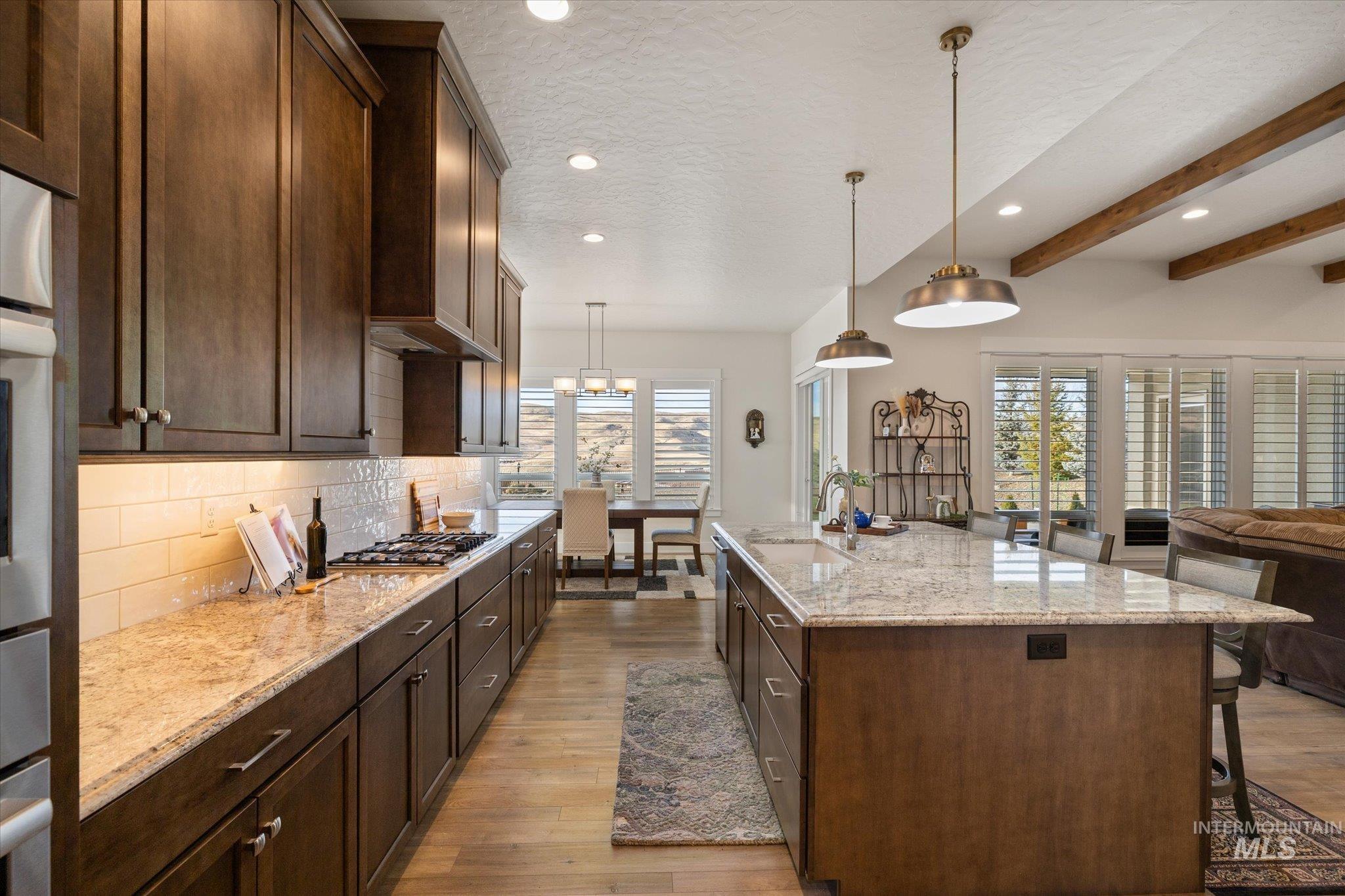 Kitchen with light stone countertops, a kitchen bar, a textured ceiling, open floor plan, and recessed lighting