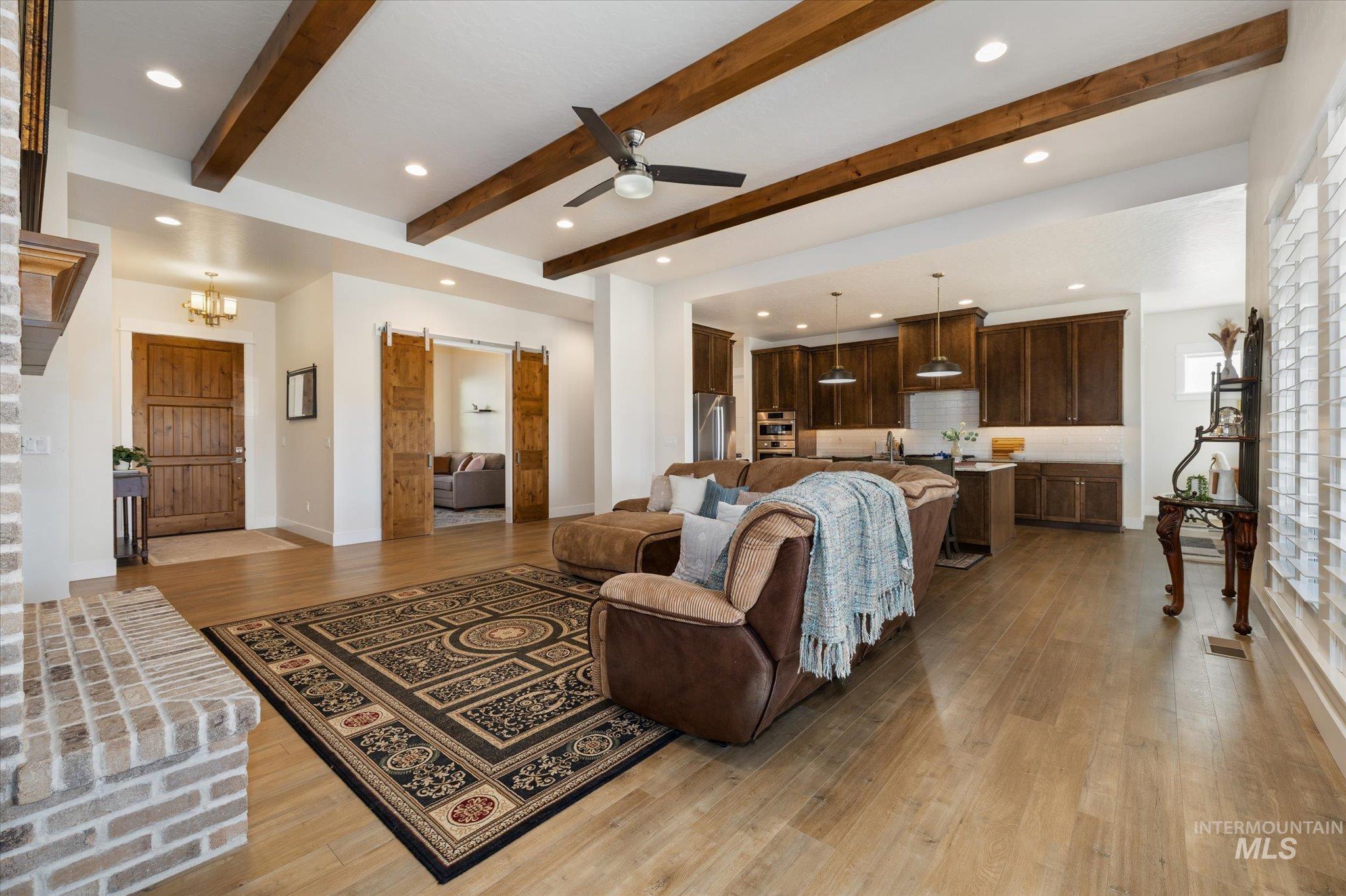 Living room featuring a barn door, recessed lighting, light wood-style floors, ceiling fan, and a chandelier
