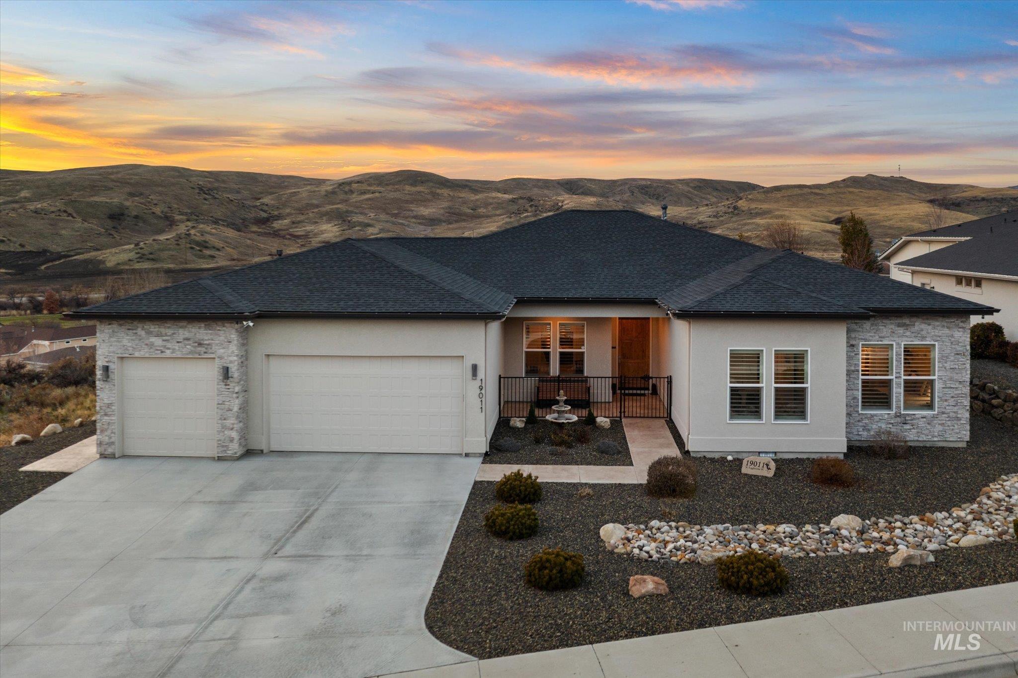 View of front facade featuring a garage, a porch, stucco siding, and a mountain view