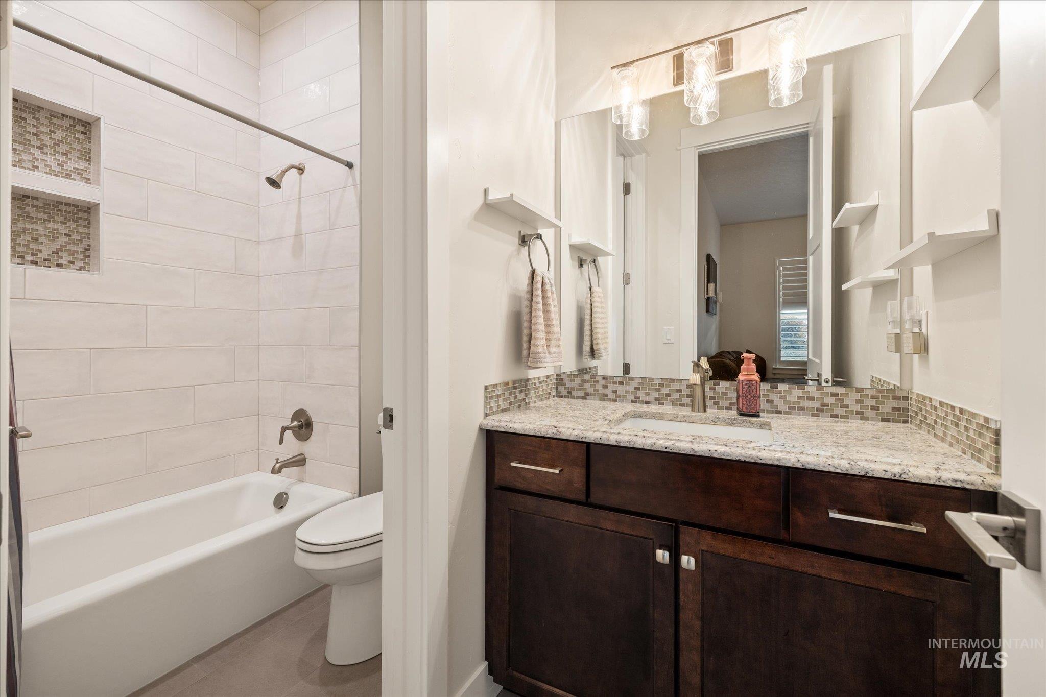 Full bath with shower / washtub combination, vanity, and tasteful backsplash