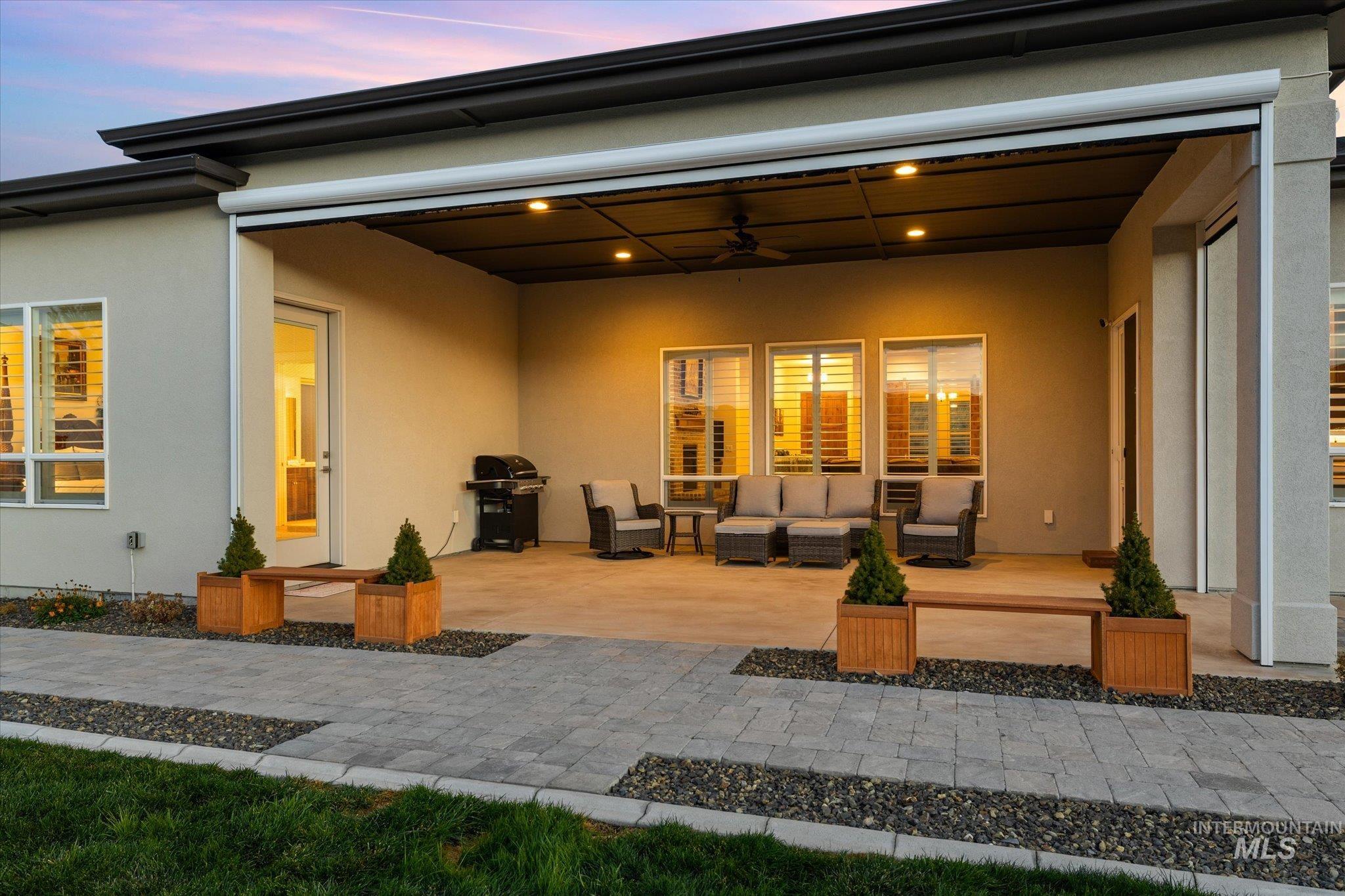 Back of house with ceiling fan, a patio area, stucco siding, and outdoor lounge area