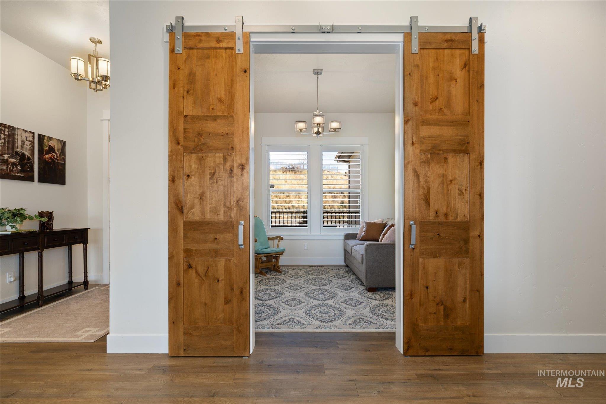 Corridor featuring a chandelier, wood finished floors, and a barn door