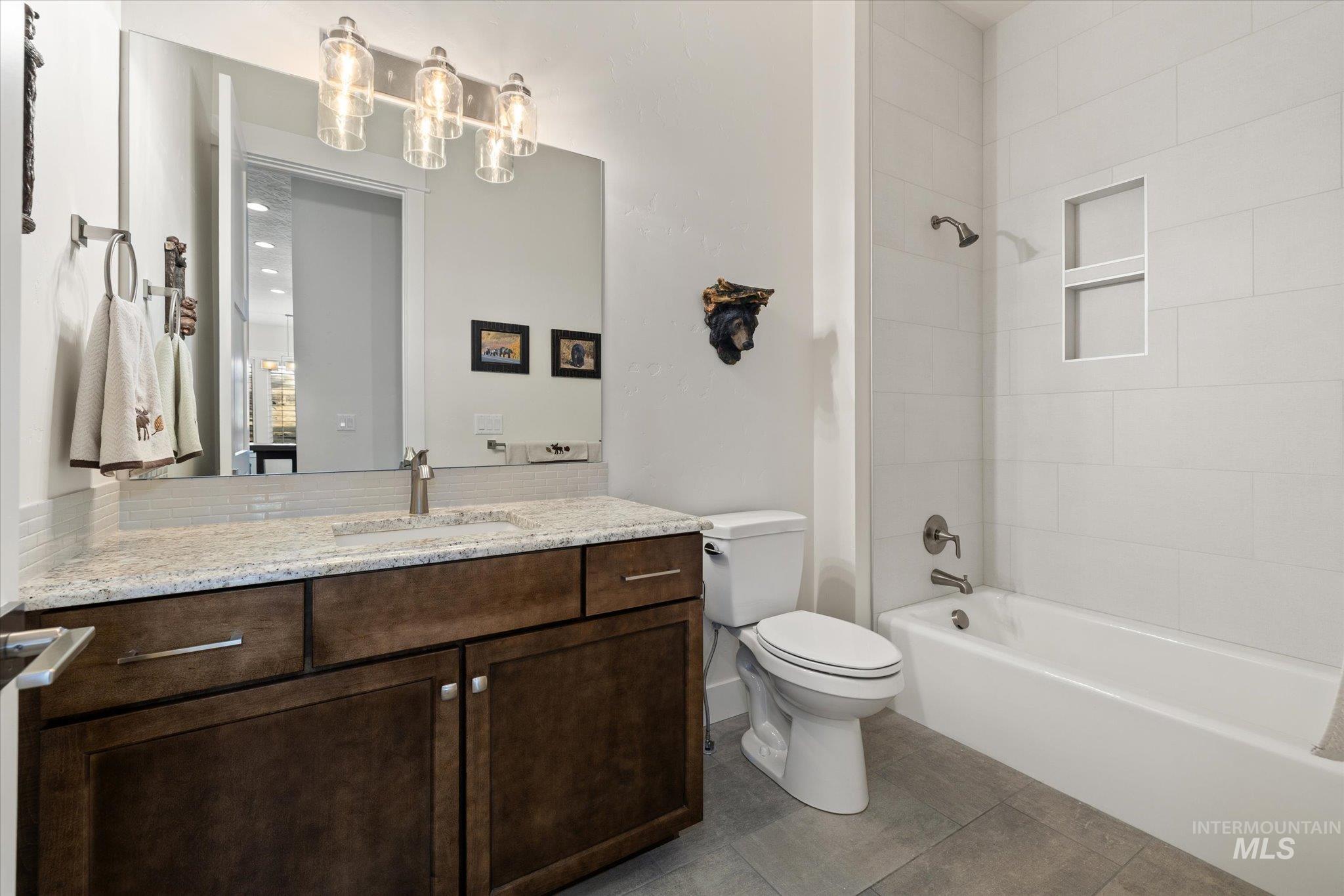 Full bath with vanity,  shower combination, and dark tile patterned flooring