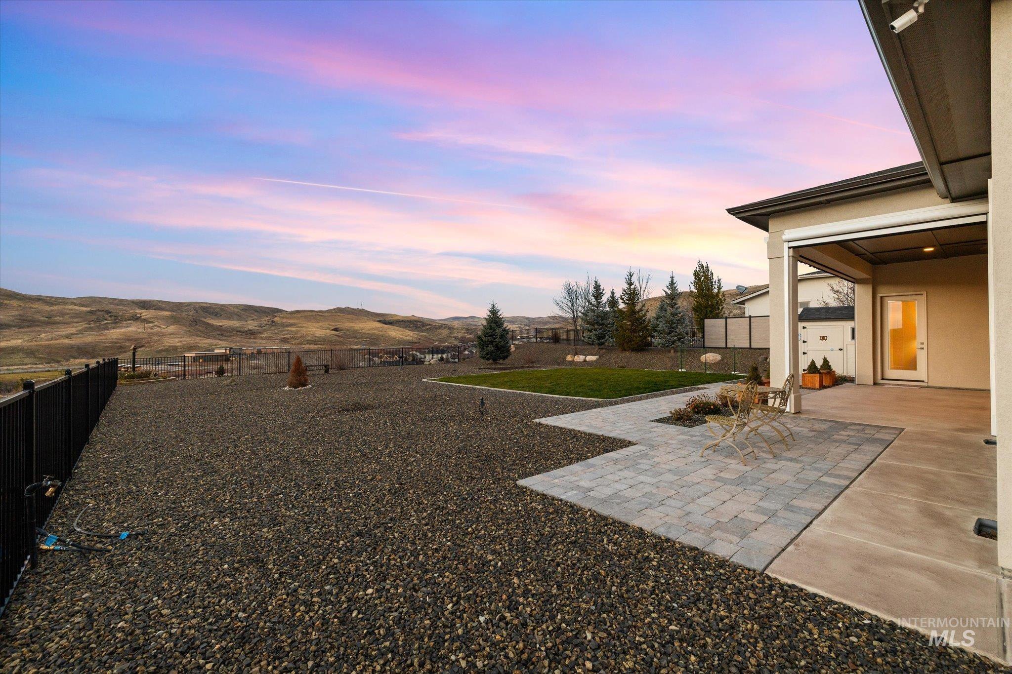 Yard at dusk with a patio area, a fenced backyard, and a mountain view