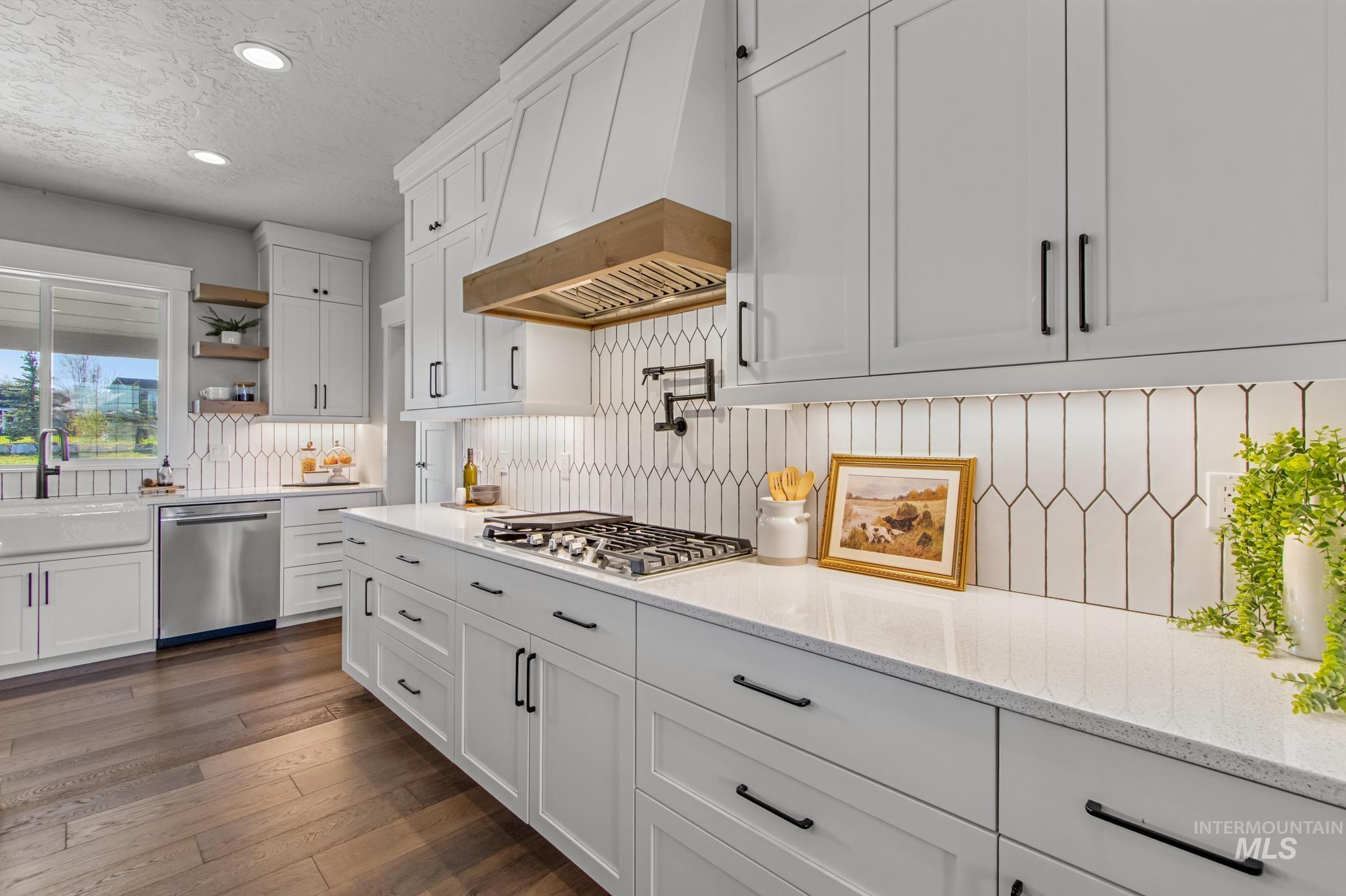 Kitchen featuring white cabinets, light stone countertops, stainless steel appliances, a textured ceiling, and dark wood finished floors